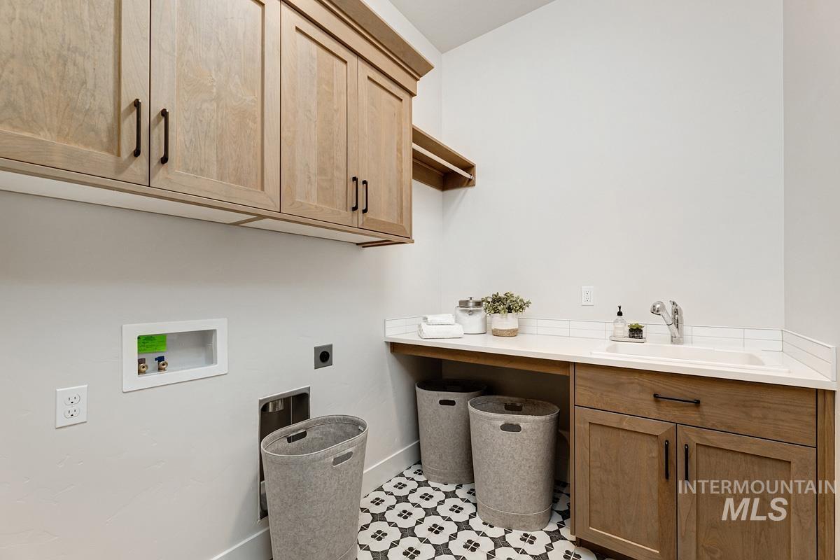 Washroom with electric dryer hookup, cabinet space, hookup for a washing machine, and light tile patterned floors