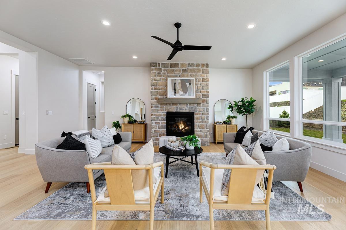 Living area featuring light wood finished floors, a ceiling fan, recessed lighting, and a fireplace