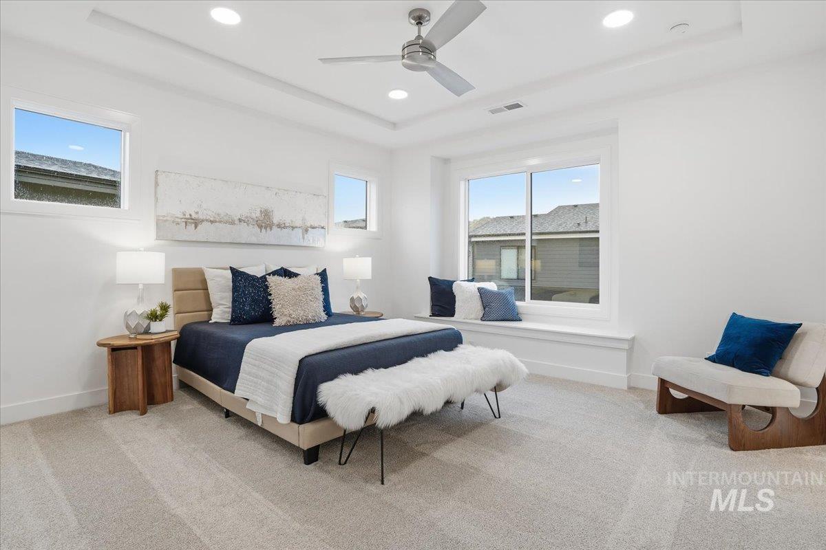 Carpeted bedroom featuring a ceiling fan, a tray ceiling, and recessed lighting