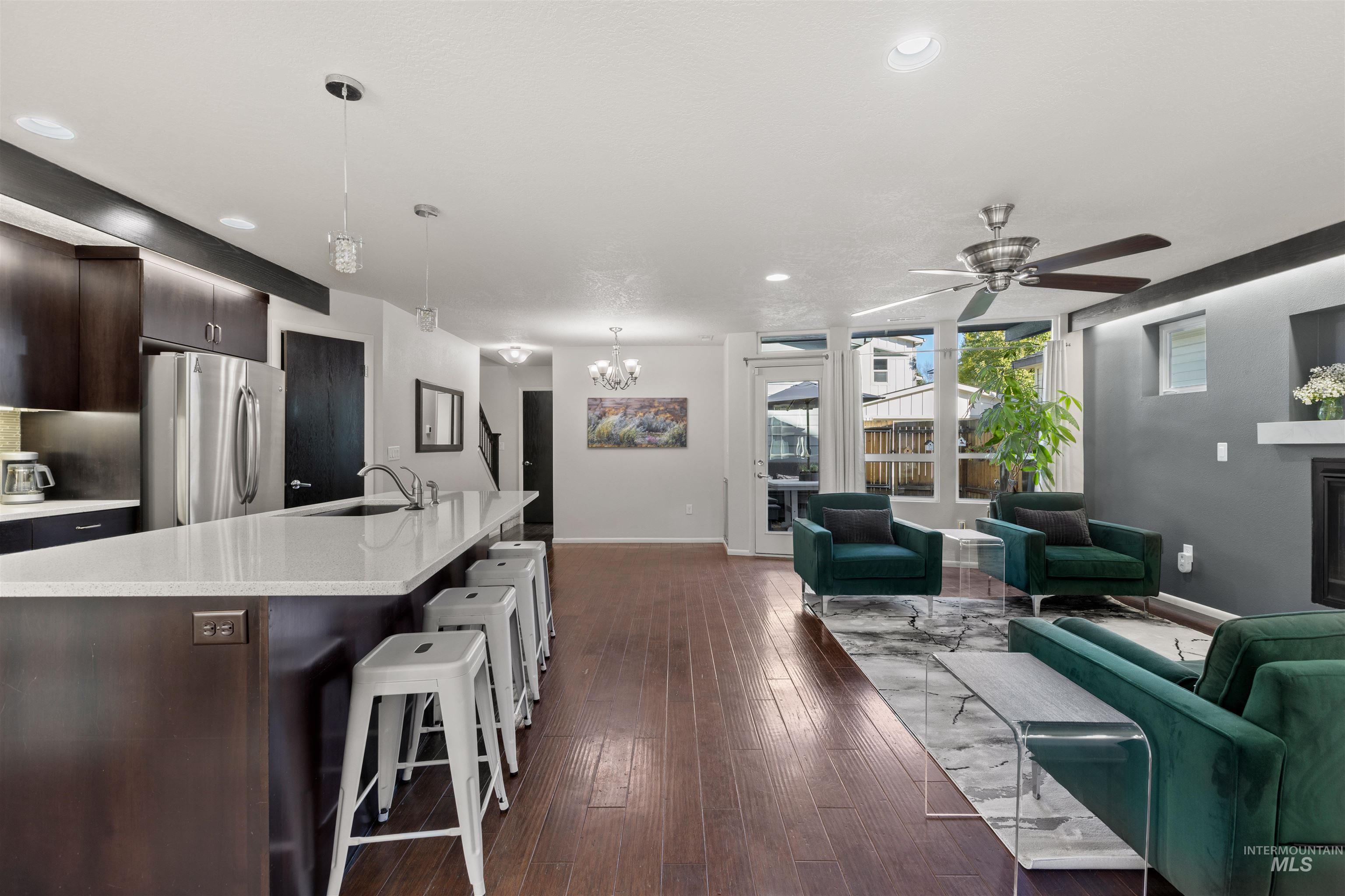Living room featuring dark wood-style floors, a ceiling fan, a chandelier, recessed lighting, and a fireplace