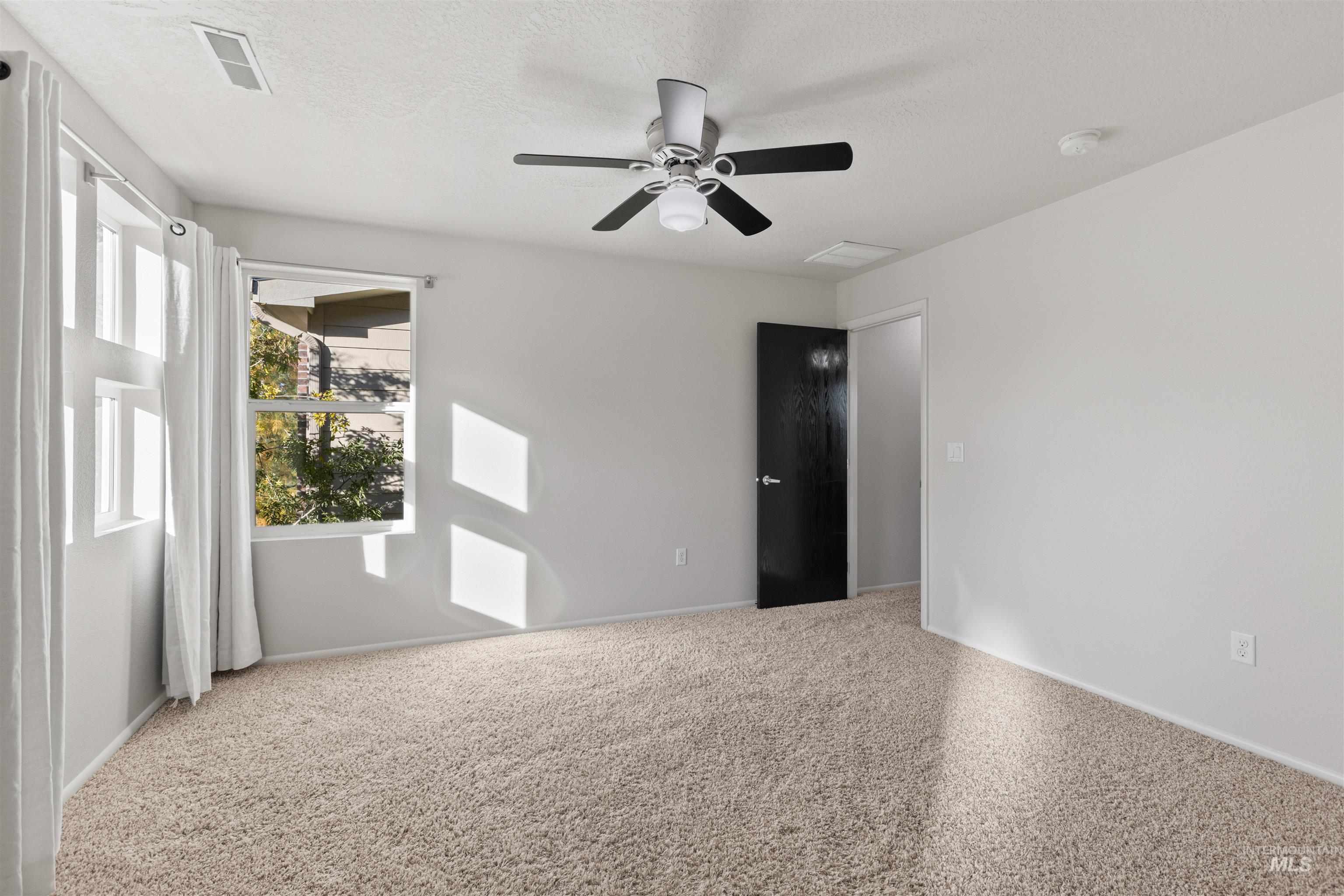 Unfurnished bedroom with a ceiling fan, carpet floors, and a textured ceiling