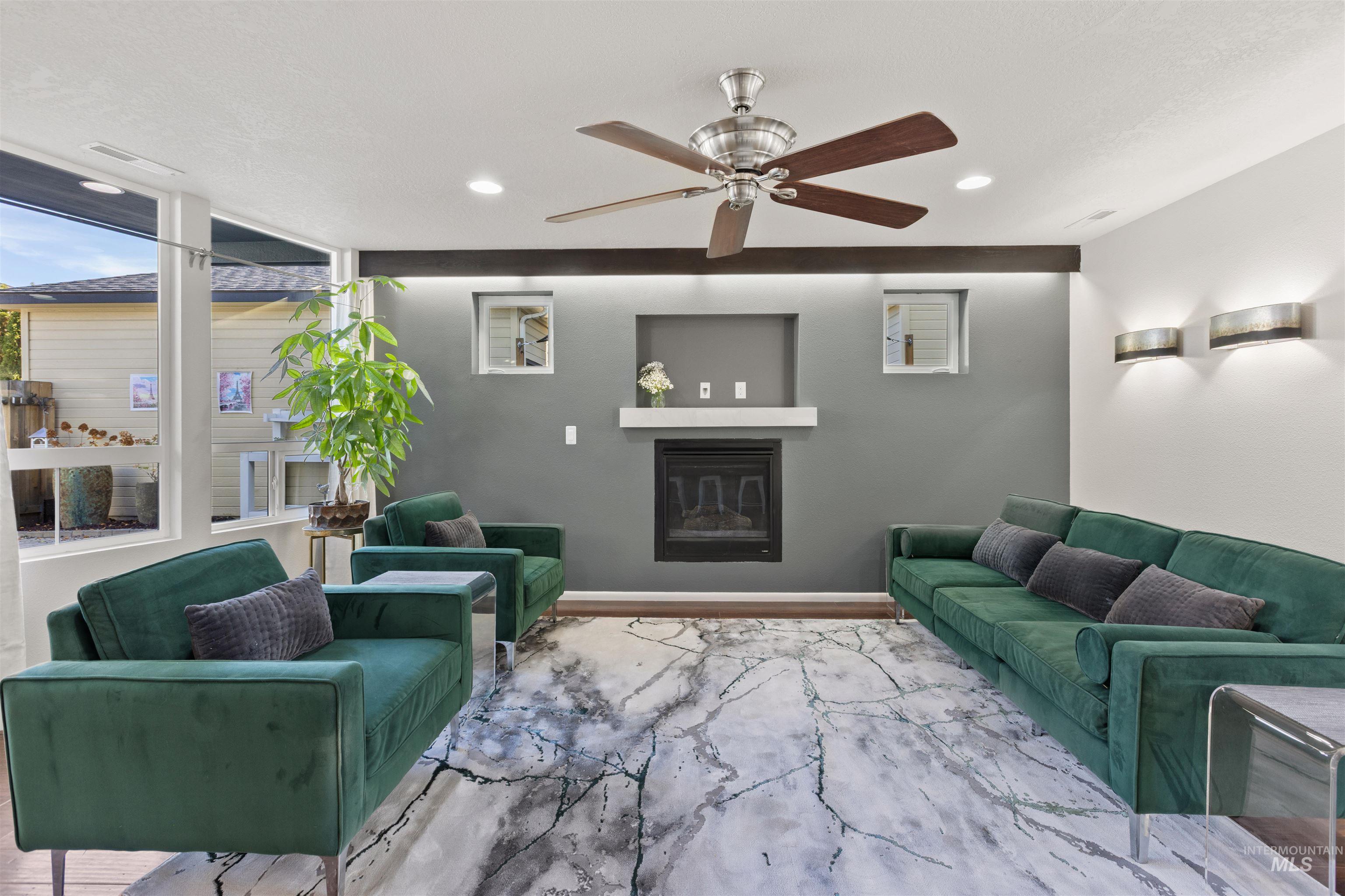 Living room with a glass covered fireplace, ceiling fan, wood finished floors, and recessed lighting