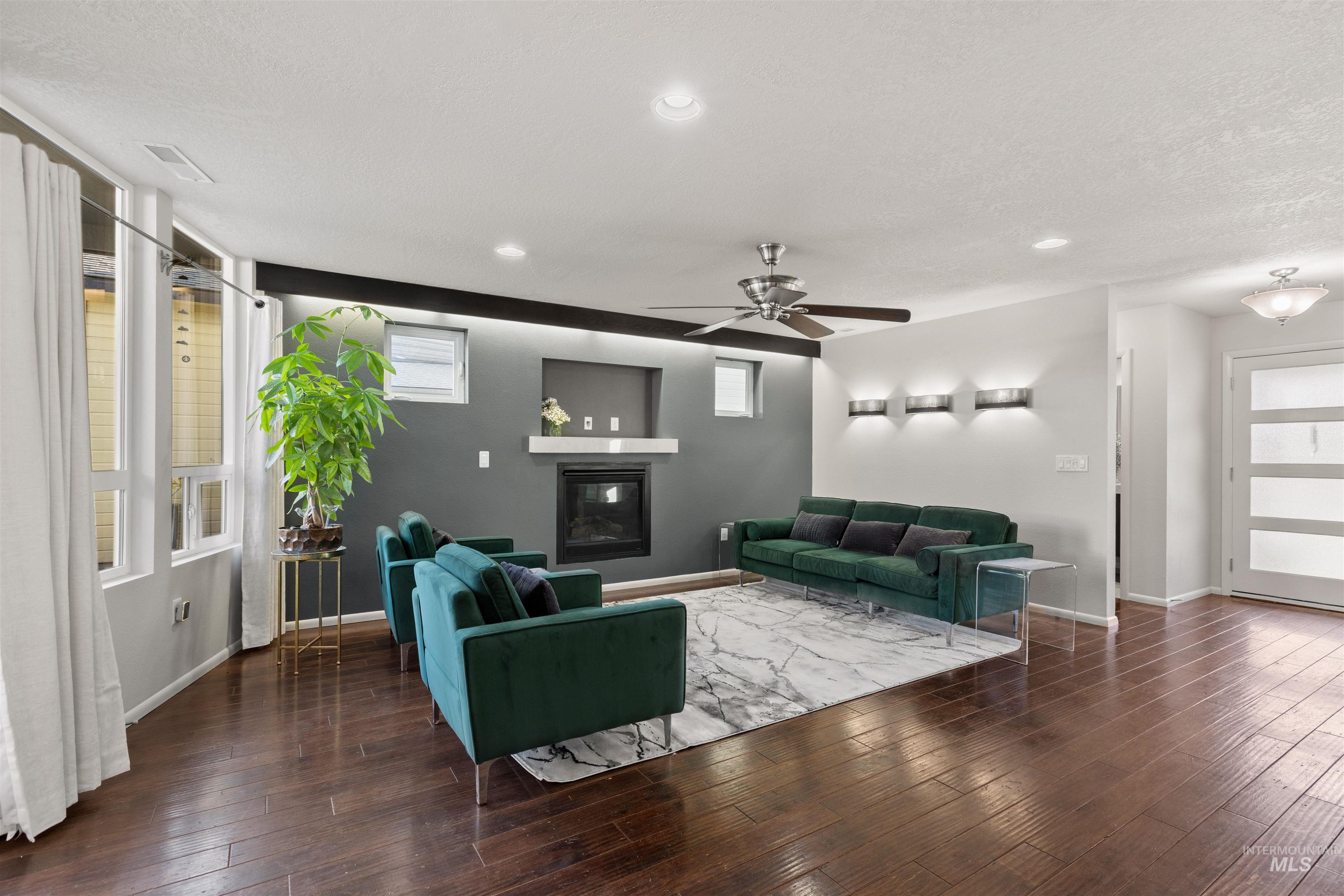 Living area with dark wood finished floors, ceiling fan, a glass covered fireplace, a textured ceiling, and recessed lighting