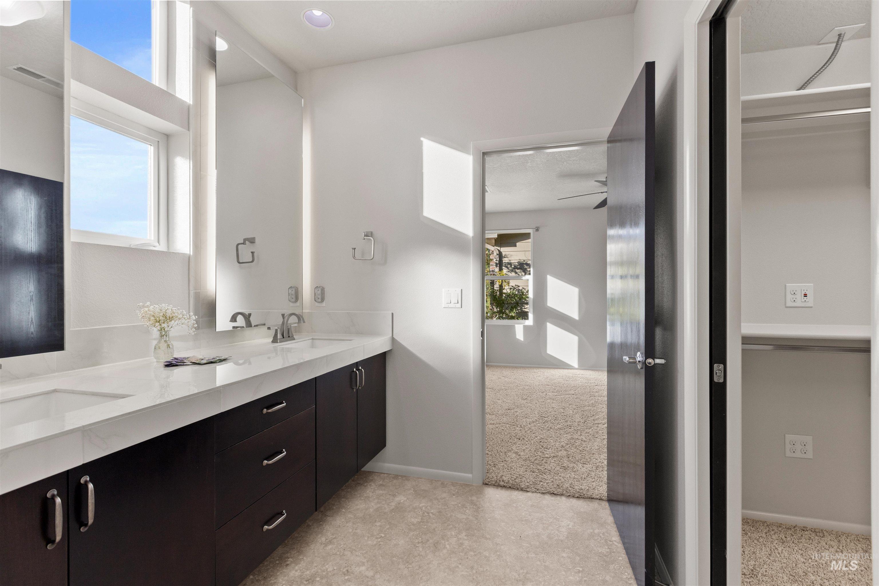 Bathroom featuring plenty of natural light, double vanity, and light colored carpet