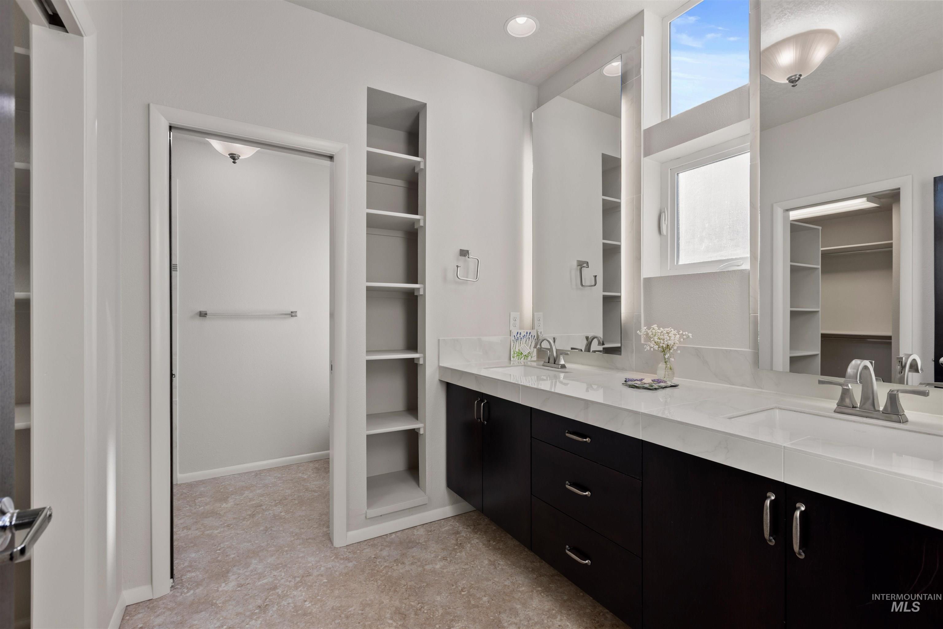 Bathroom with a walk in closet, double vanity, and recessed lighting