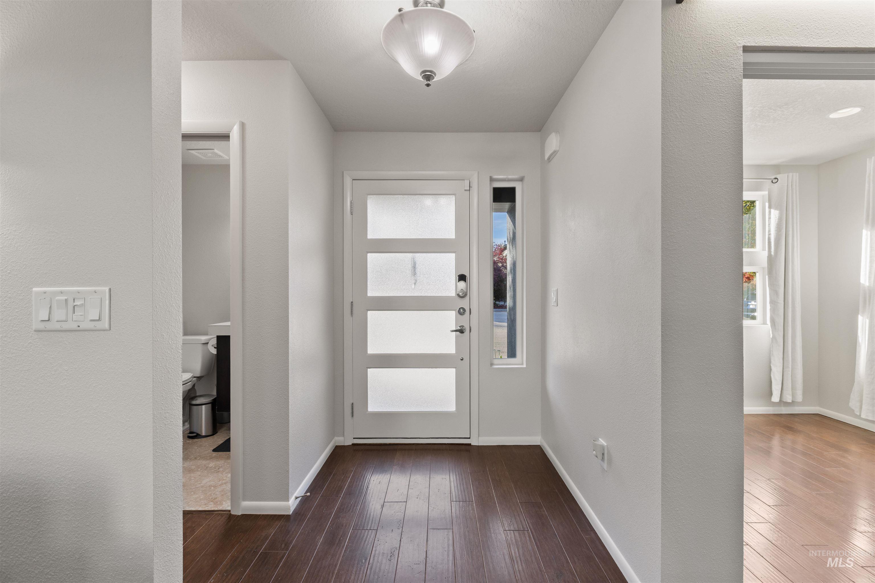 Foyer entrance with dark wood finished floors and a textured wall