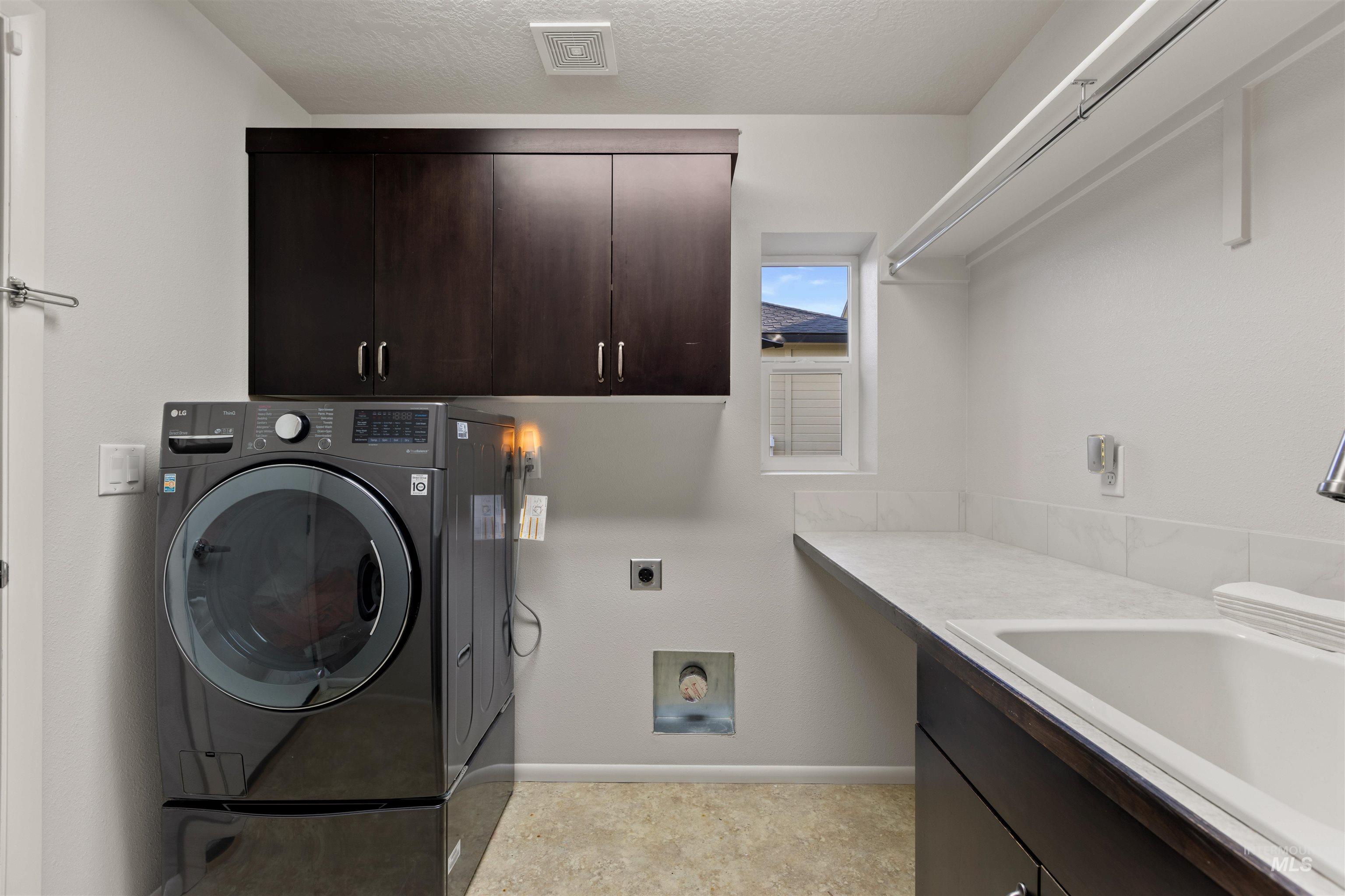 Laundry area featuring washer / clothes dryer, cabinet space, and a textured ceiling