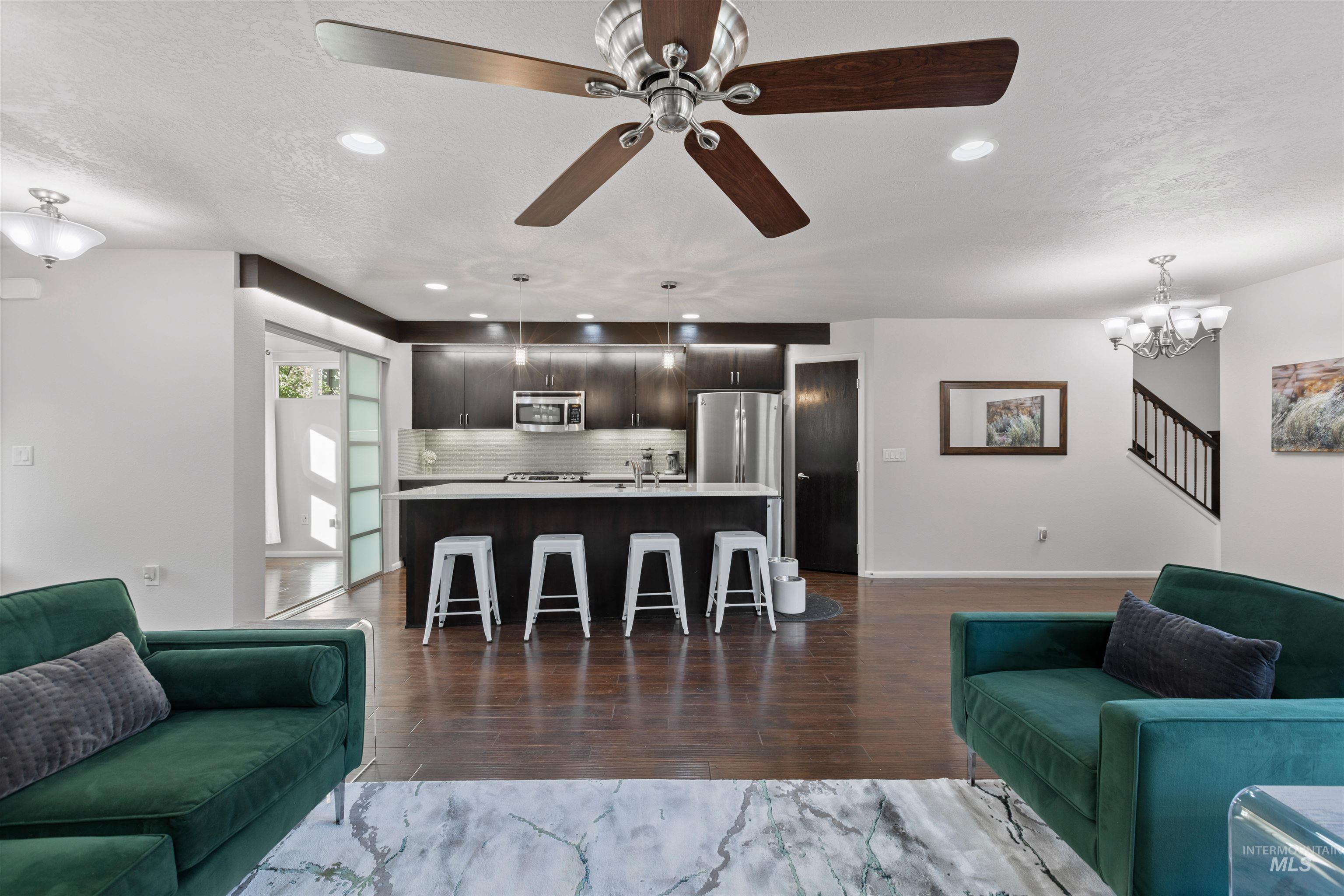 Living room featuring dark wood-type flooring, a textured ceiling, stairs, a ceiling fan, and recessed lighting
