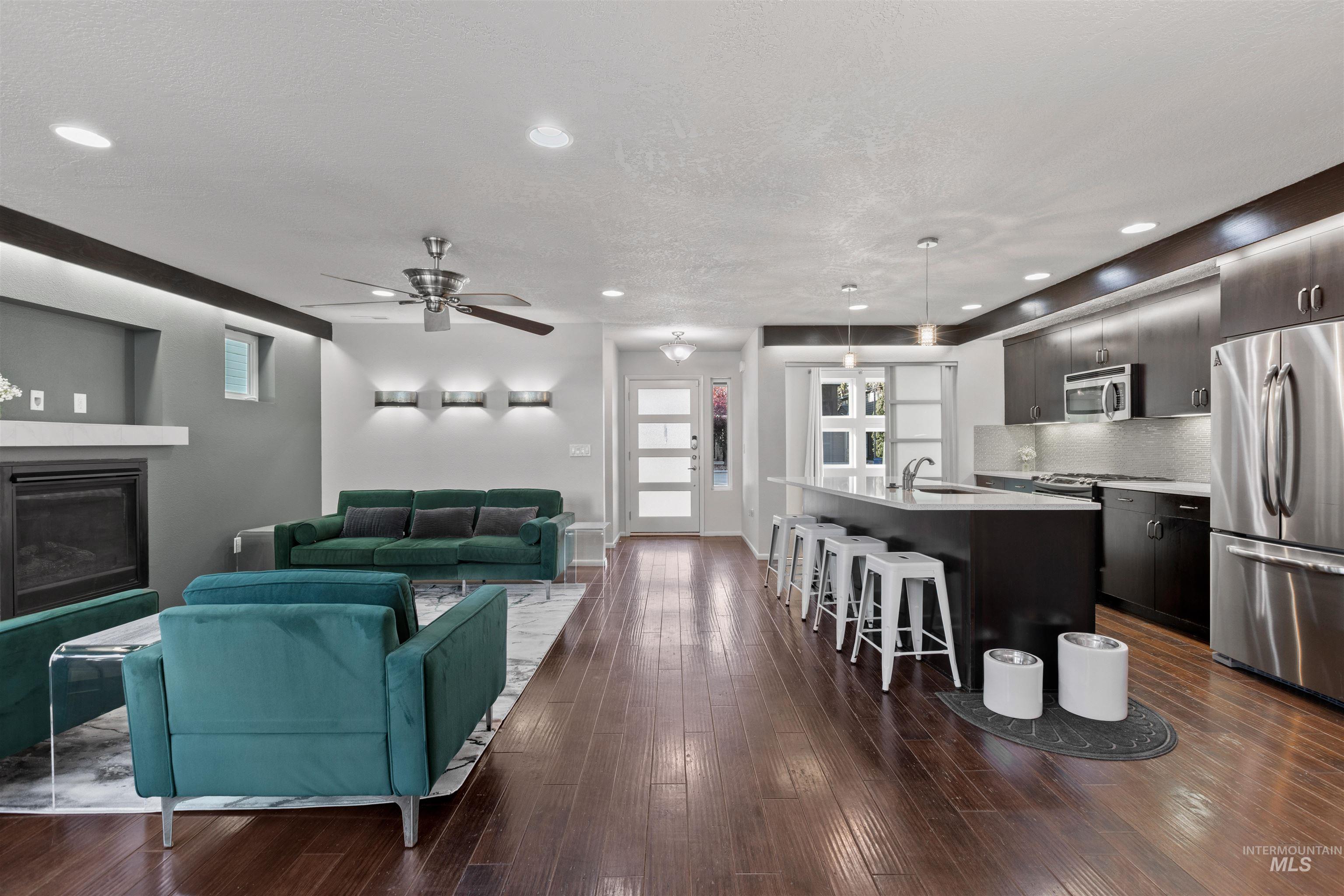 Living area featuring dark wood-style floors, ceiling fan, a textured ceiling, recessed lighting, and a glass covered fireplace