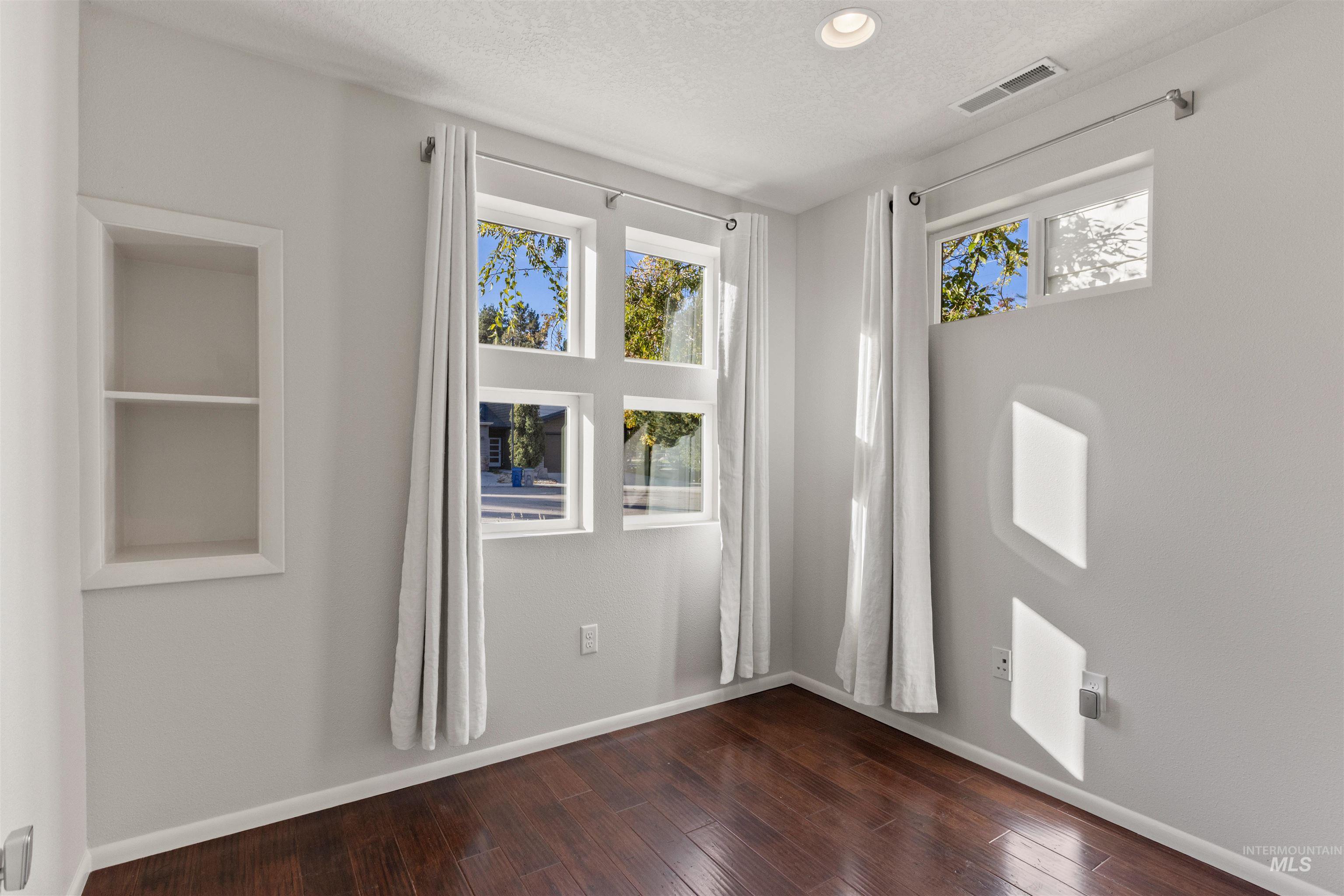 Spare room with dark wood-style floors, plenty of natural light, a textured ceiling, and recessed lighting