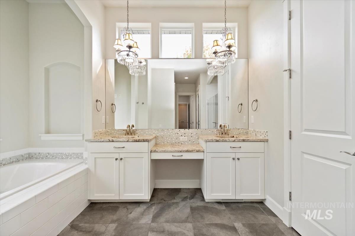 Bathroom featuring double vanity, a garden tub, dark tile patterned flooring, and a towering ceiling