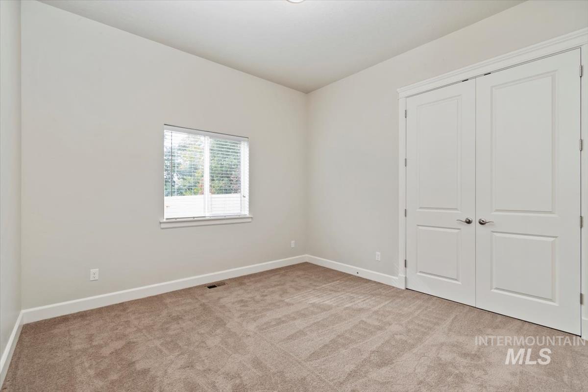 Unfurnished bedroom with light colored carpet and a closet