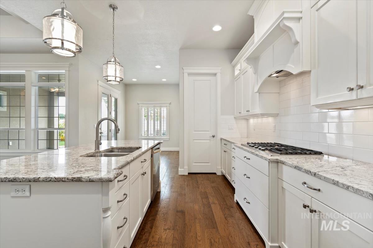 Kitchen featuring white cabinetry, dark wood-style flooring, light stone countertops, decorative light fixtures, and recessed lighting