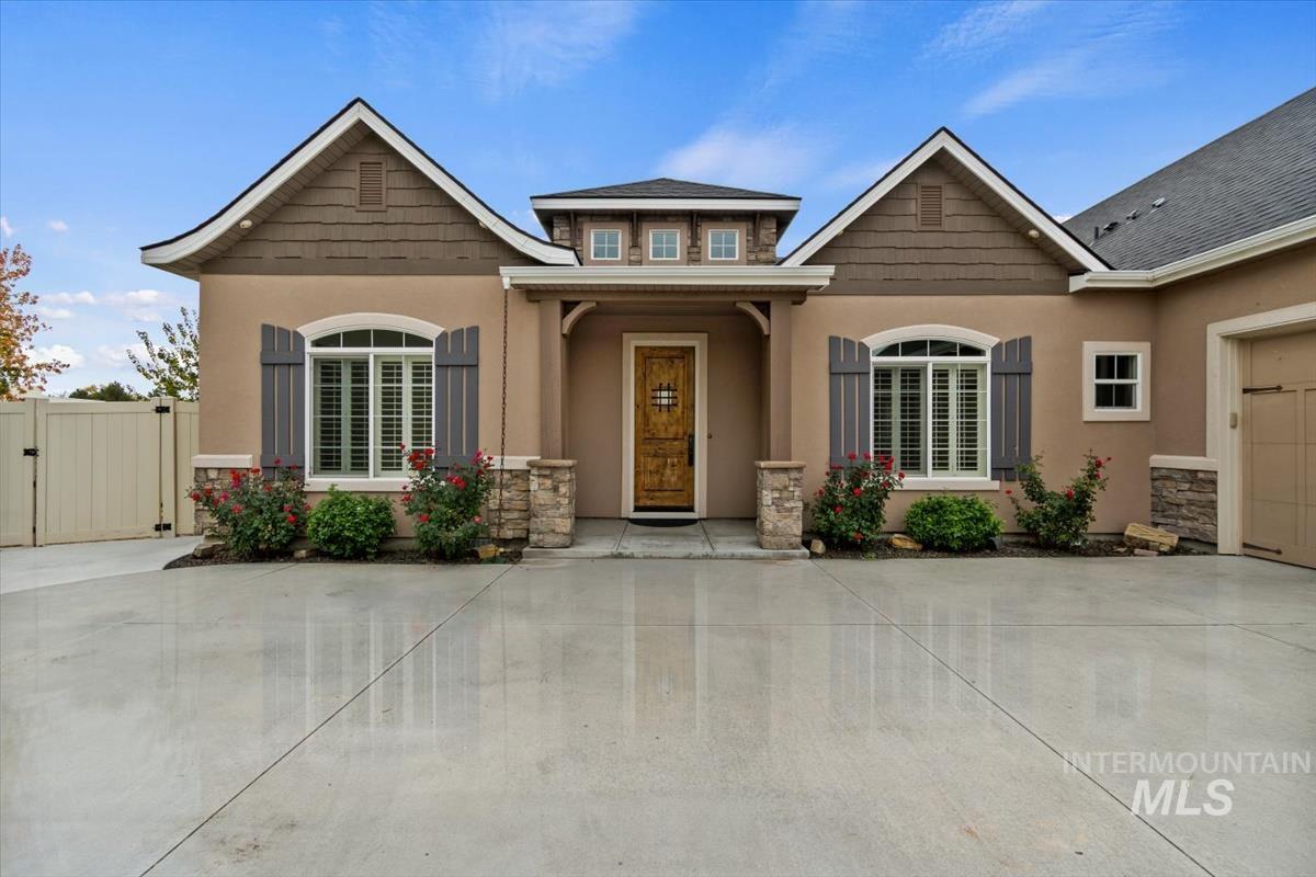 View of front of property with stone siding, a gate, stucco siding, concrete driveway, and a garage