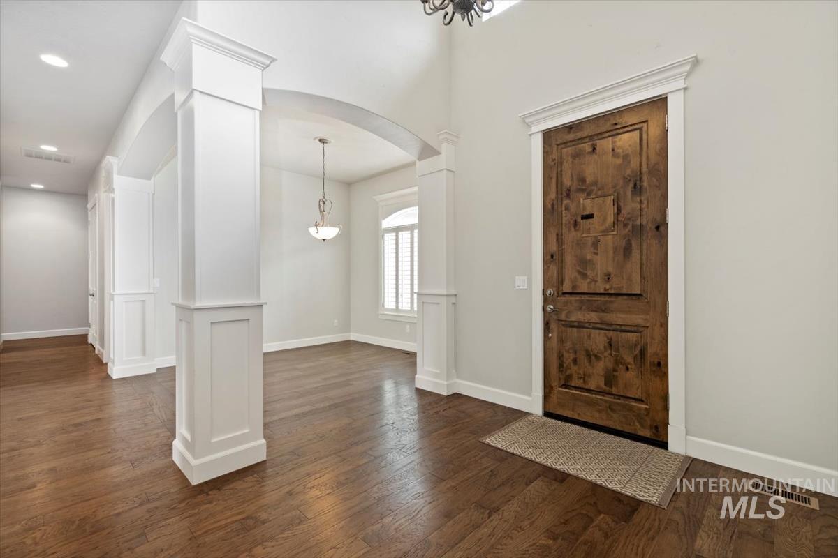 Entryway featuring arched walkways, dark wood finished floors, ornate columns, and recessed lighting