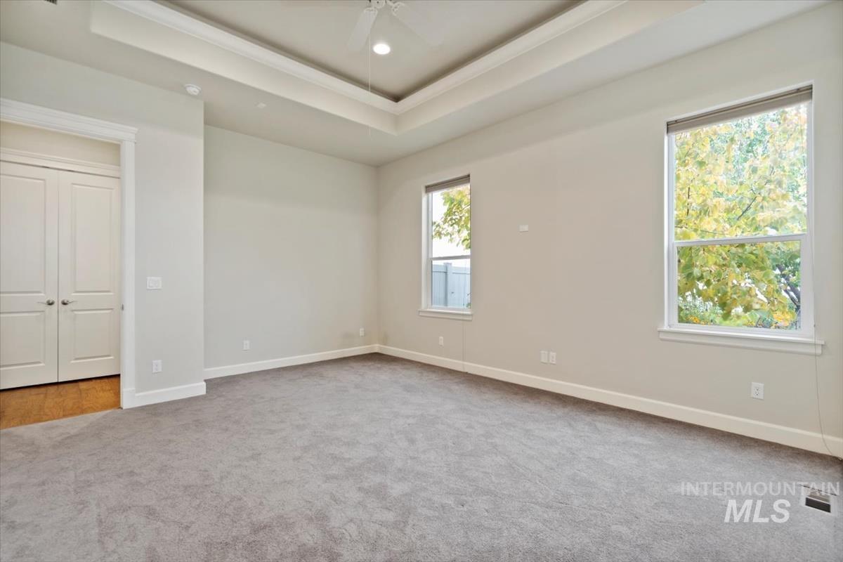 Unfurnished bedroom with a raised ceiling, light carpet, crown molding, a ceiling fan, and recessed lighting
