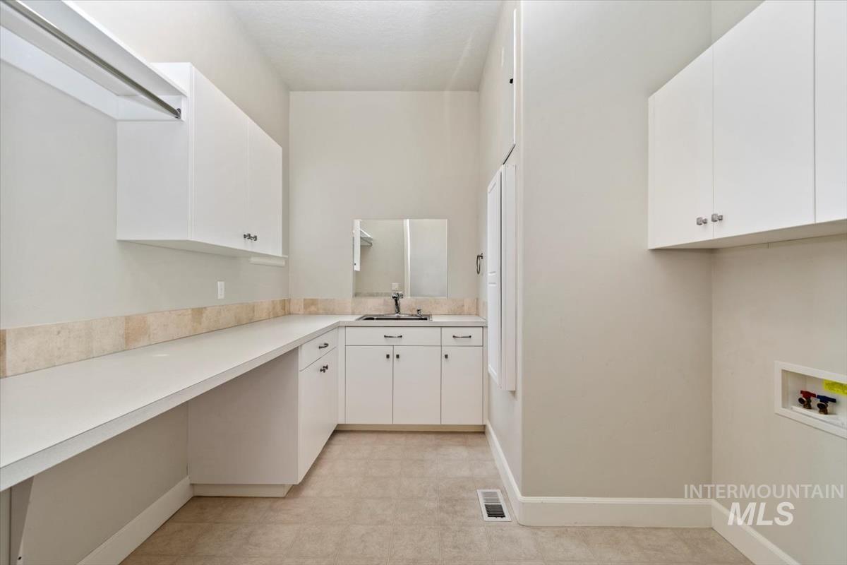 Laundry area with cabinet space, light flooring, and washer hookup