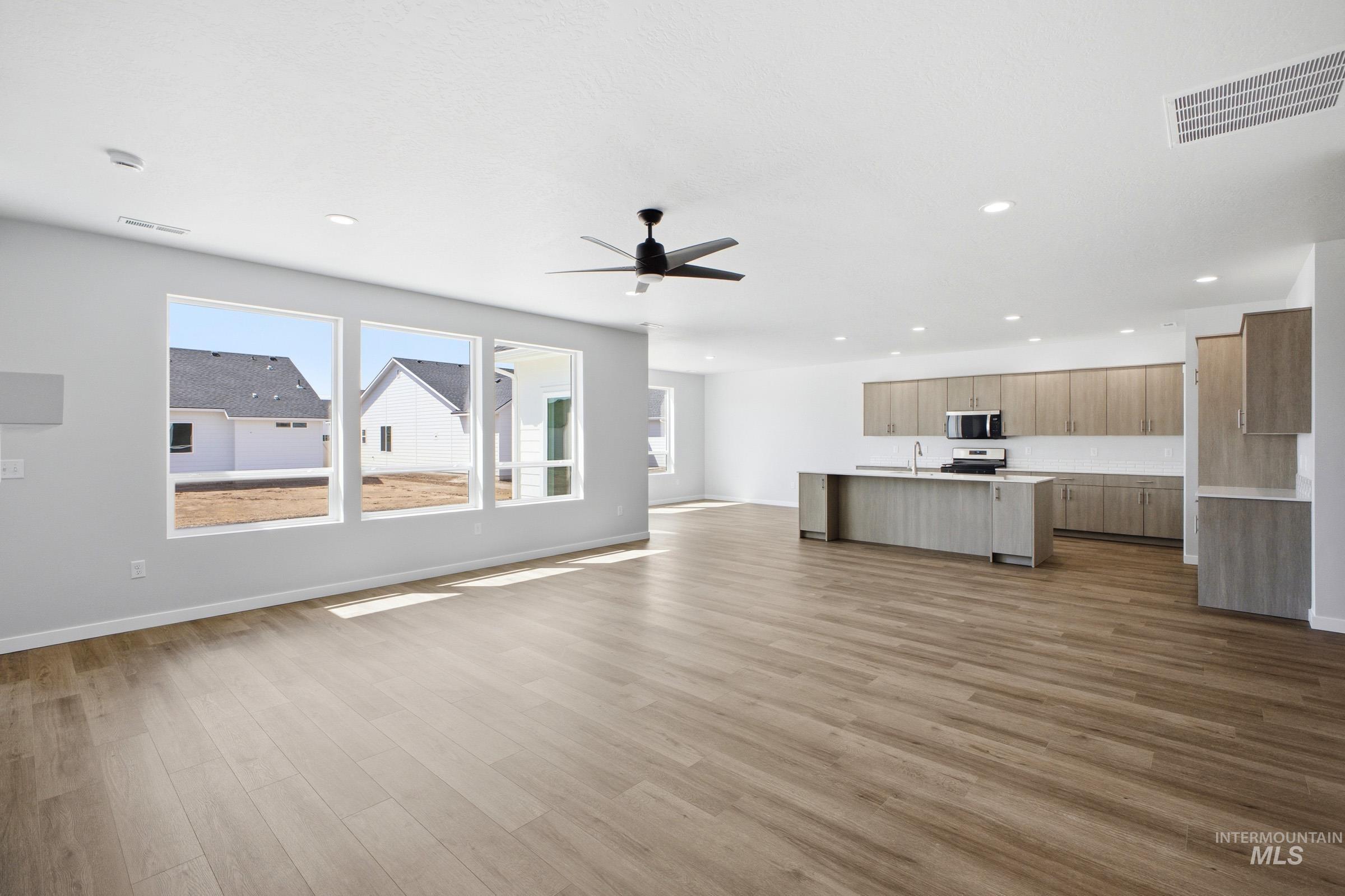Open-concept living space featuring wood-finish flooring, recessed lighting, and a contemporary ceiling fan