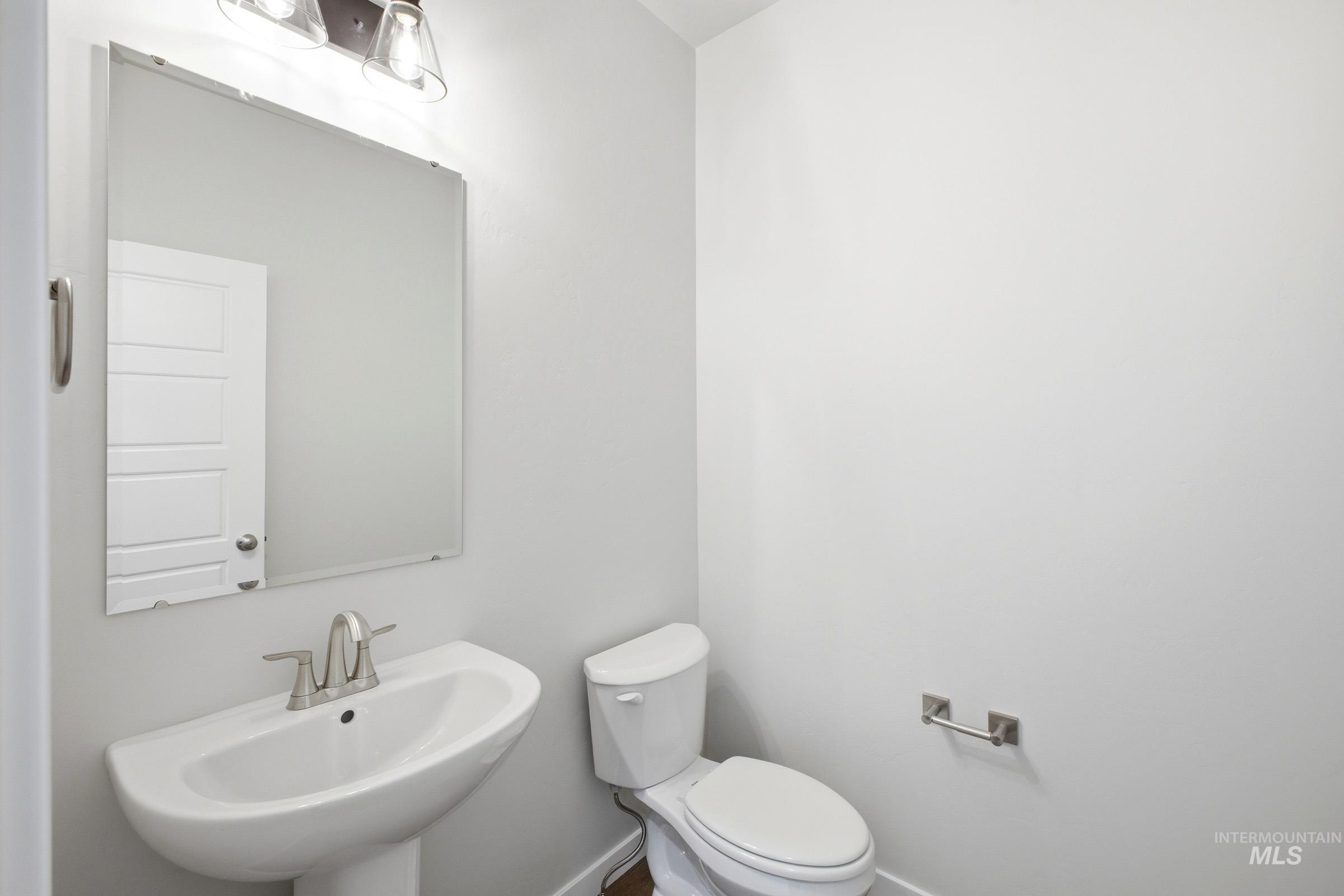 Pedestal sink with brushed nickel faucet, large wall mirror, and modern vanity lighting