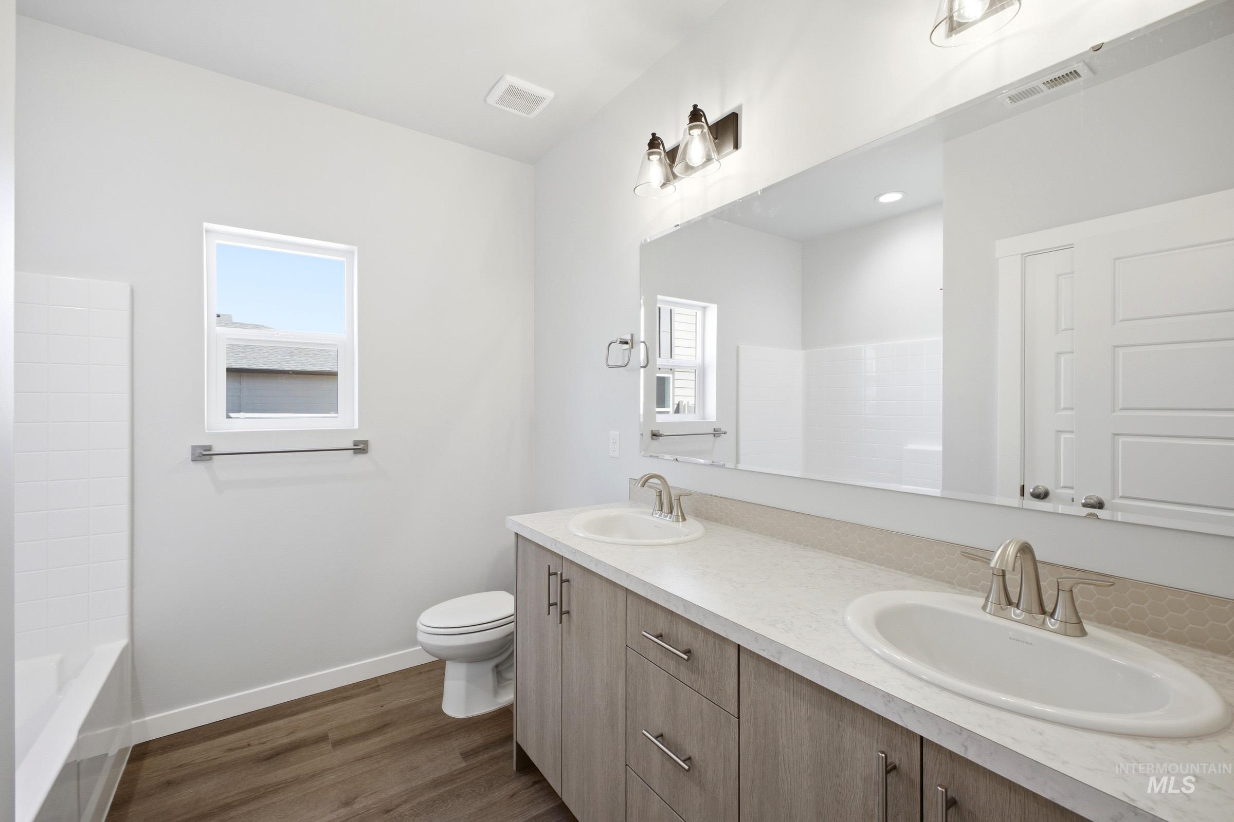 Bathroom featuring a dual vanity with light wood-finish cabinetry and light-toned countertops