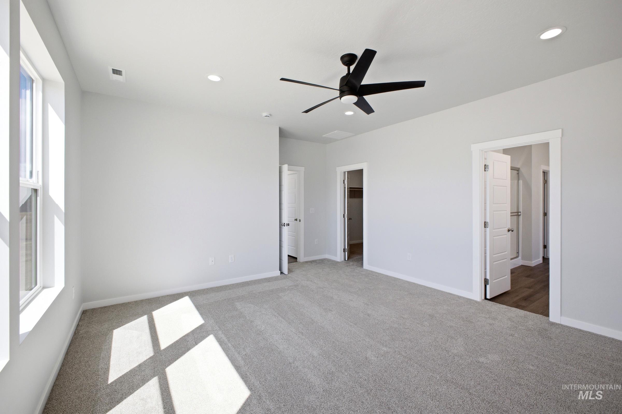 Spacious room featuring light-toned carpeting, multiple recessed ceiling lights, and a contemporary black ceiling fan