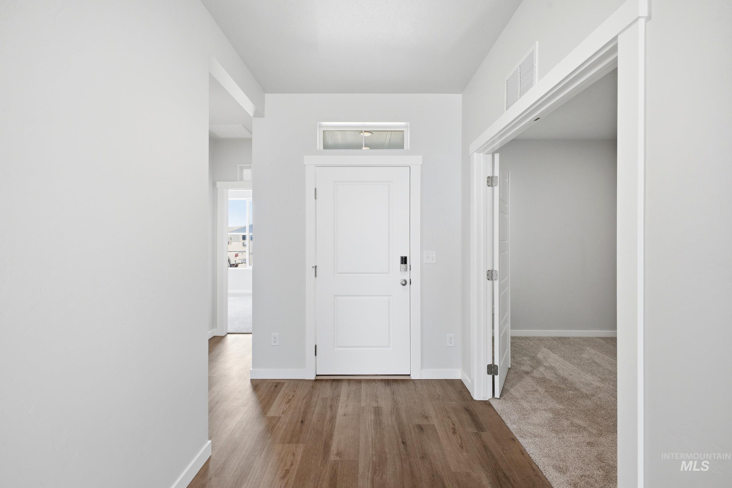 Entryway featuring wood-finish flooring, a contemporary white door with smart lock hardware, a transom window, and neutral wall tones