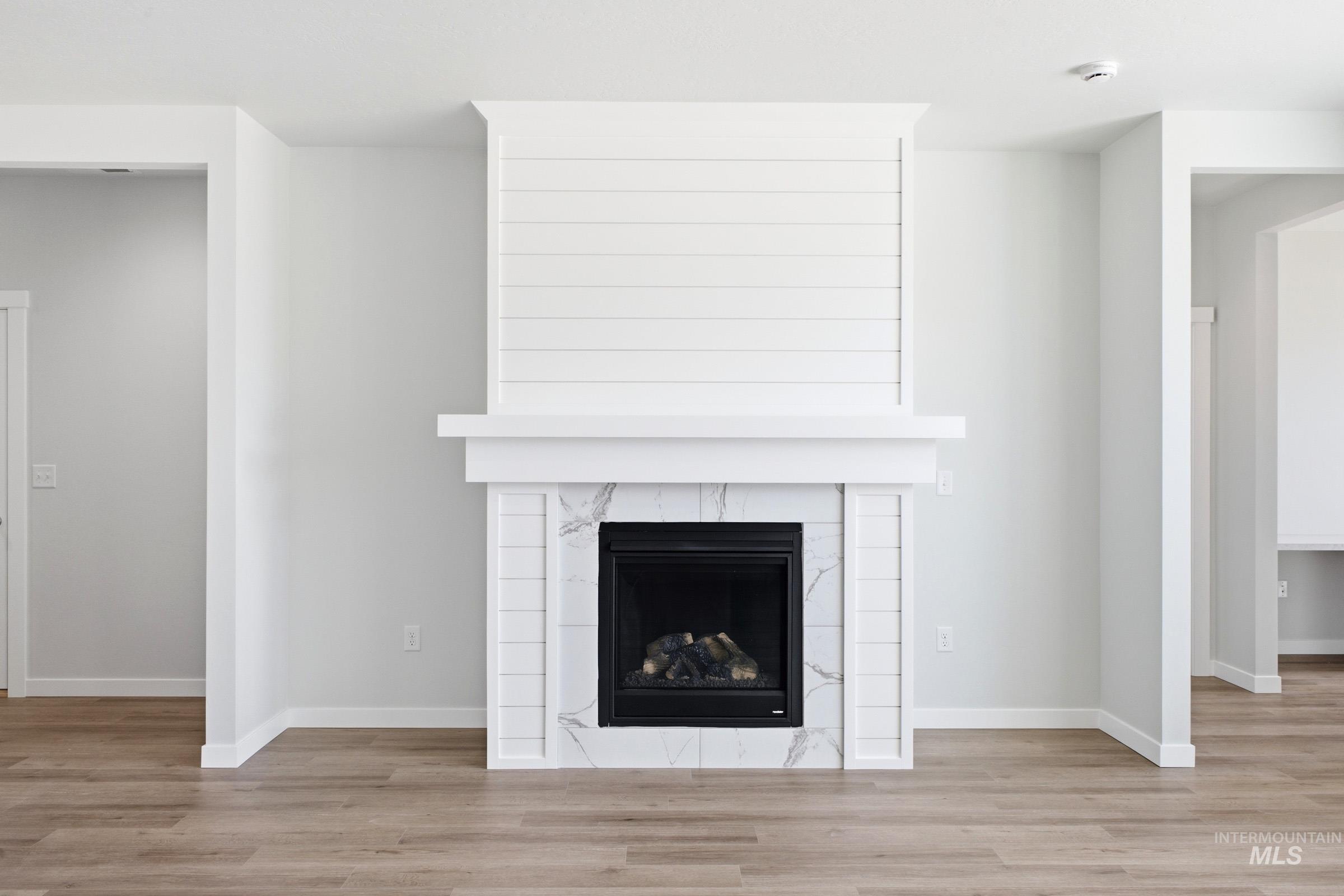 Fireplace featuring a shiplap-style surround, white mantel, and marble-look tile