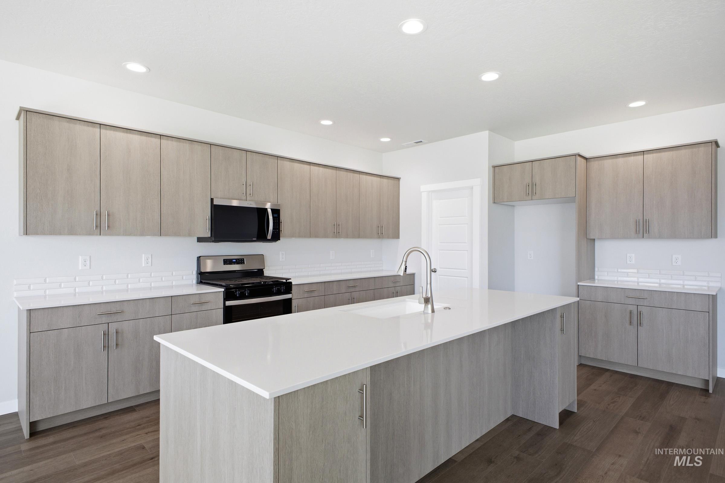 Open-concept kitchen featuring an expansive island with an undermount sink and gooseneck faucet