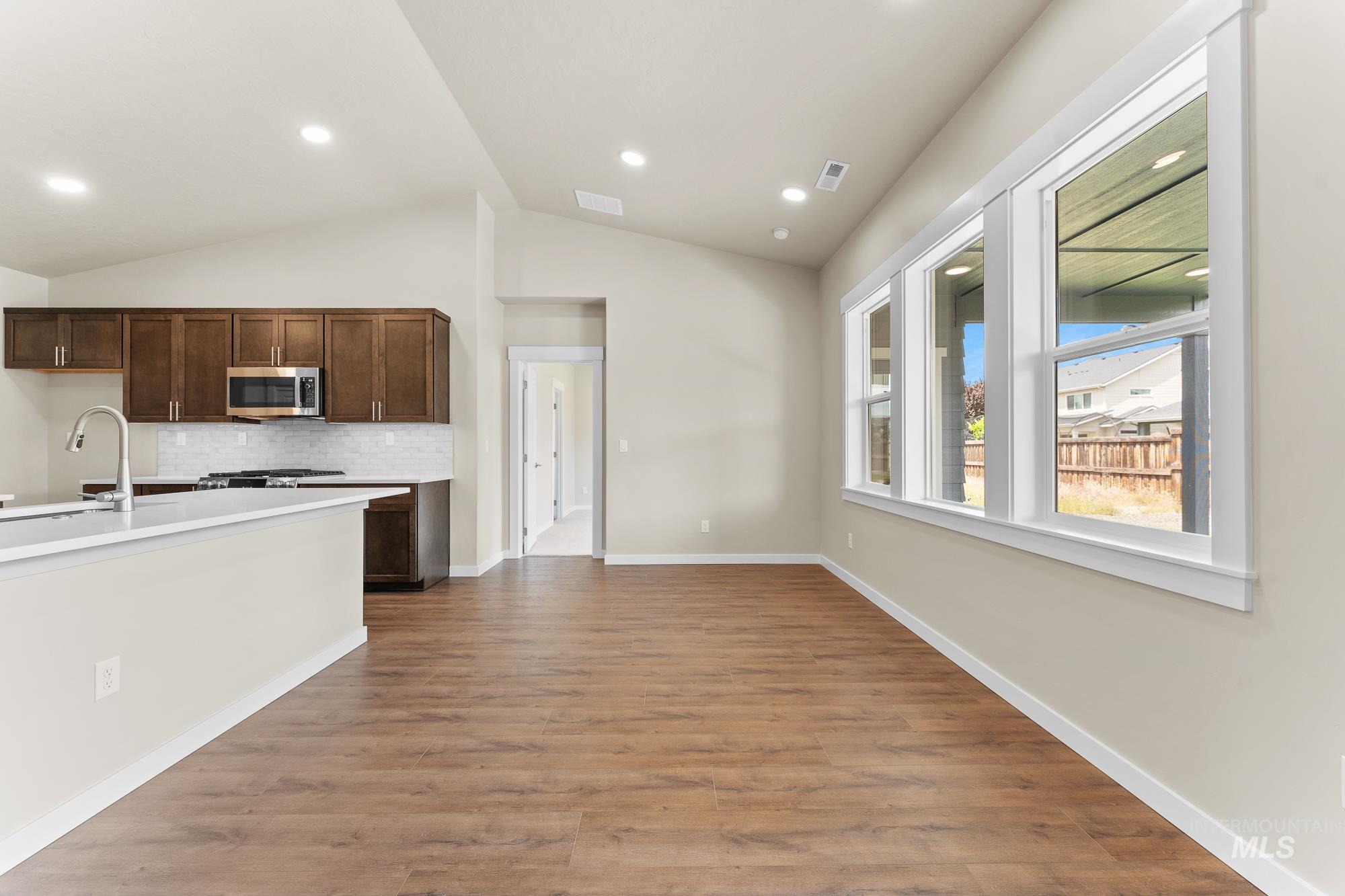 Open concept living space featuring wood-finish flooring, vaulted ceilings, and recessed lighting