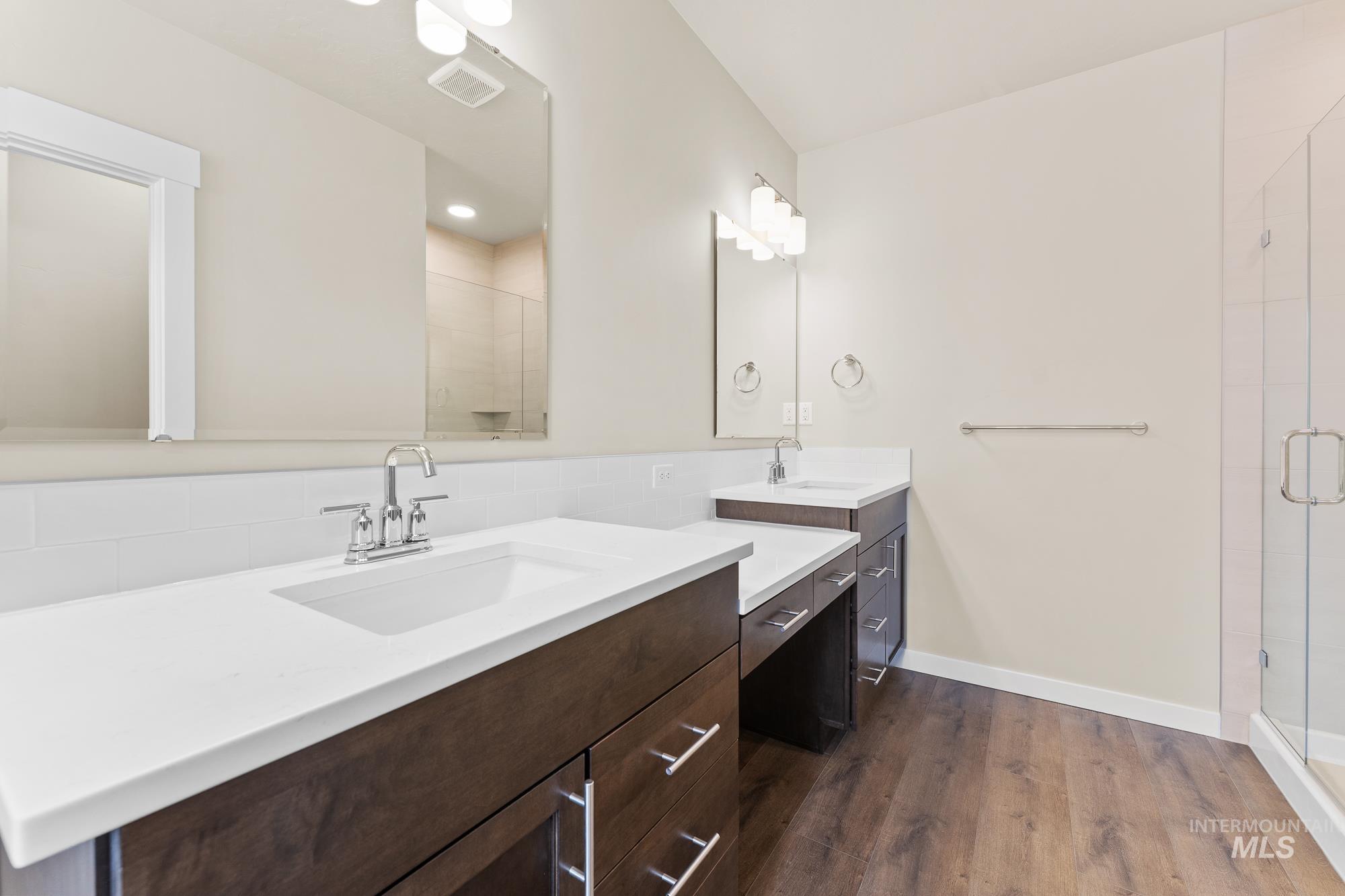 Dual vanities with white countertops, wood-finish cabinetry, and chrome fixtures