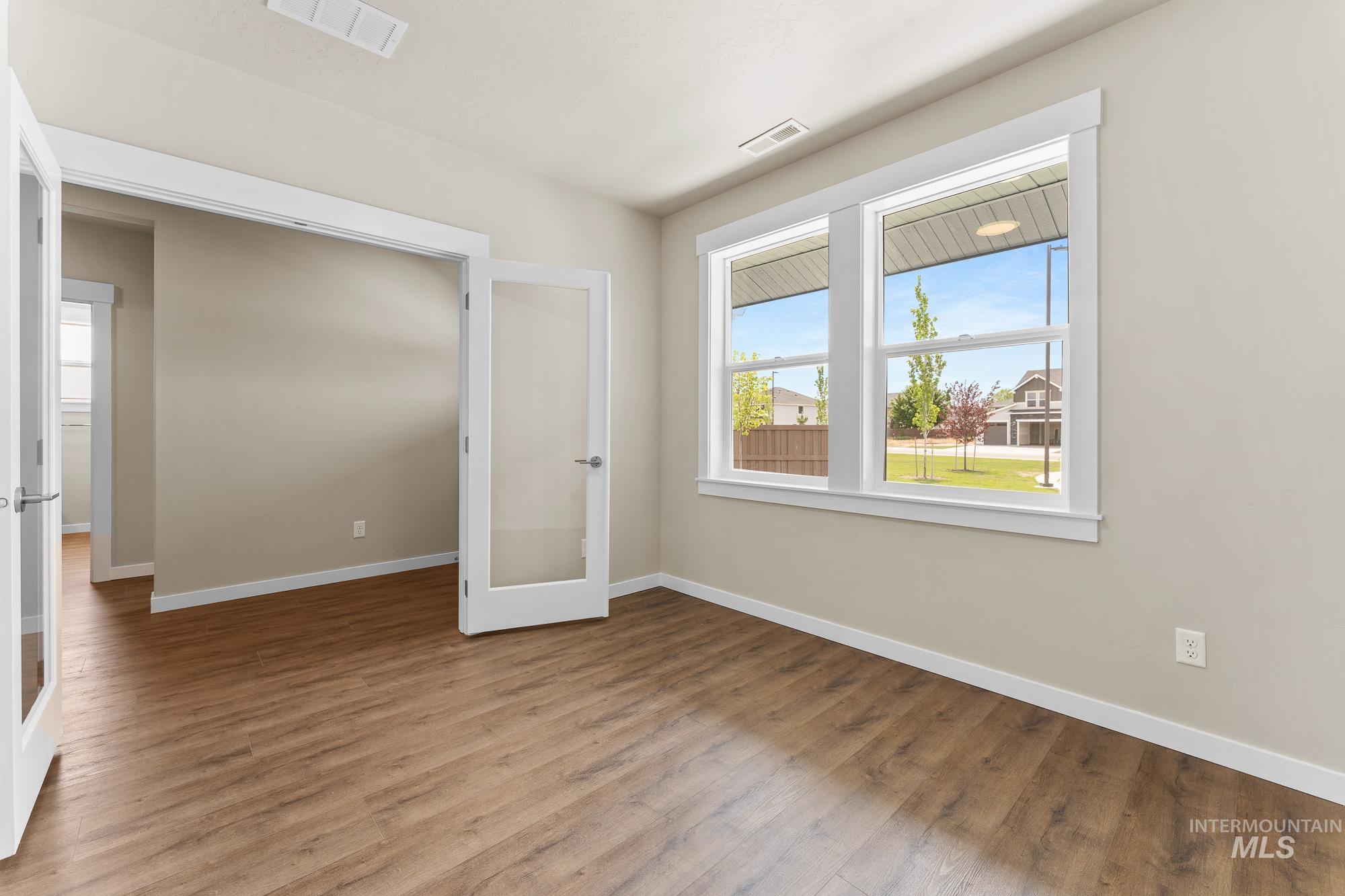 Versatile room featuring wood-finish flooring, neutral wall tones, and white trim