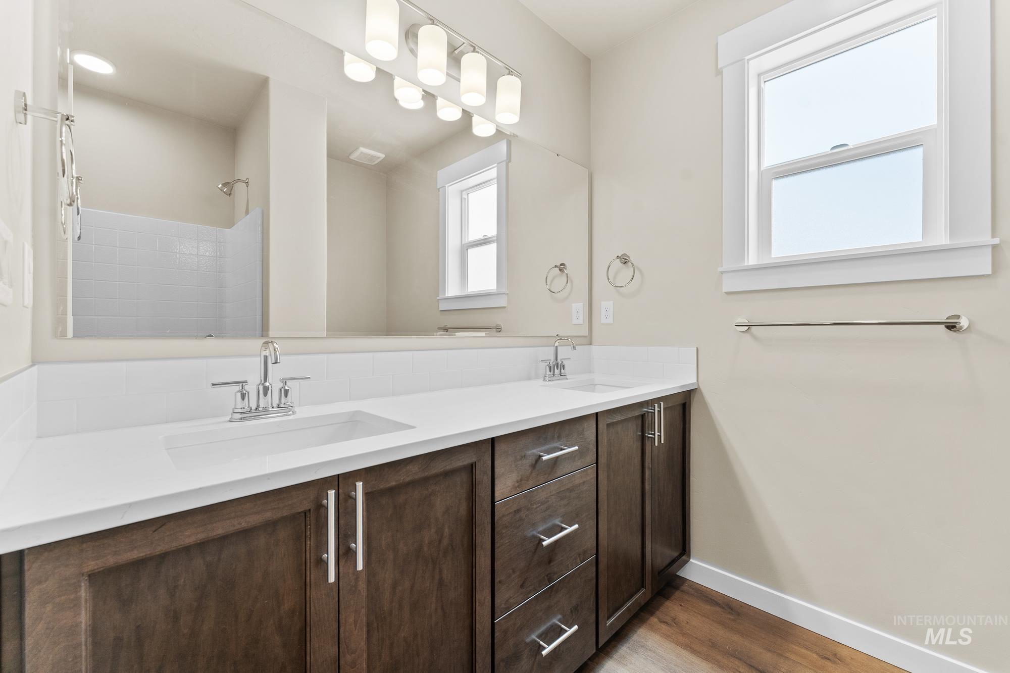 Bathroom featuring a double vanity with white countertops, integrated sinks, and dark wood-finish cabinetry