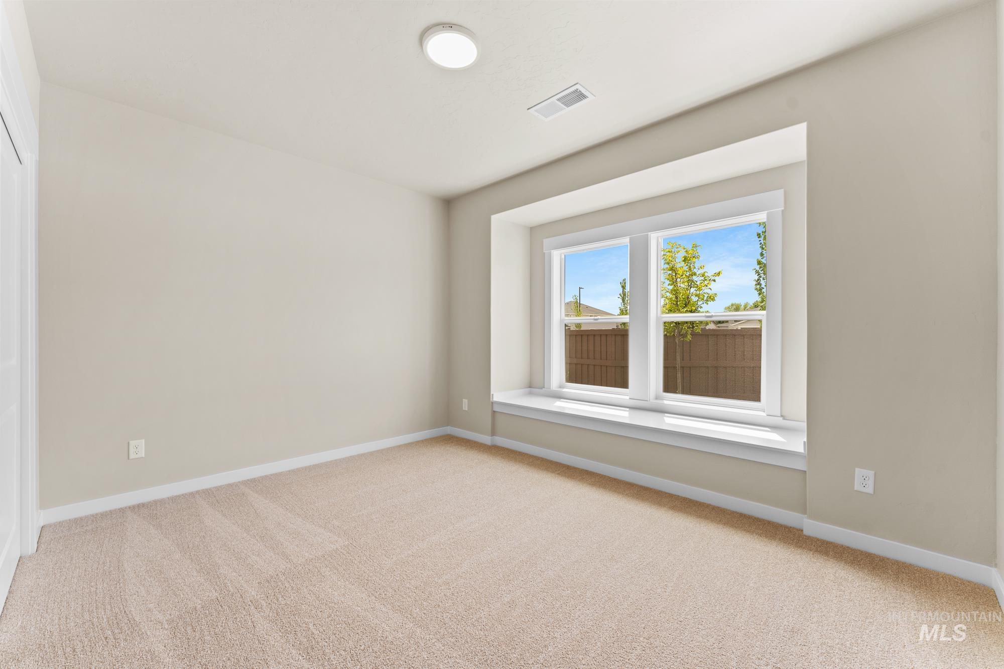 Recessed window seating with a double window, light tan carpeting, and a flush-mount ceiling light