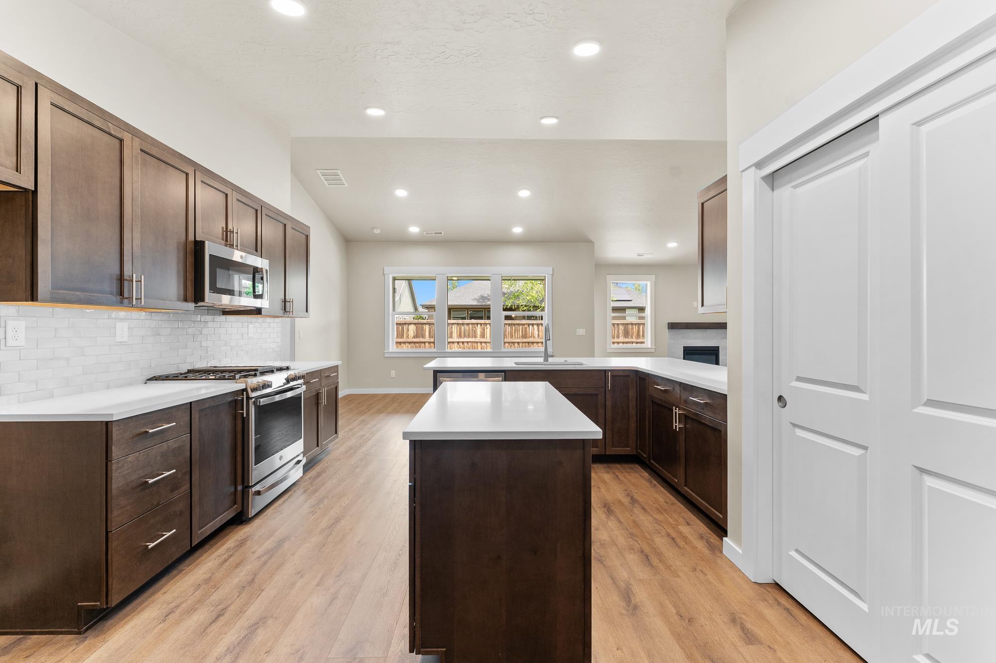 Kitchen featuring wood-finish flooring, recessed lighting, white countertops, dark wood cabinetry, and a subway tile backsplash