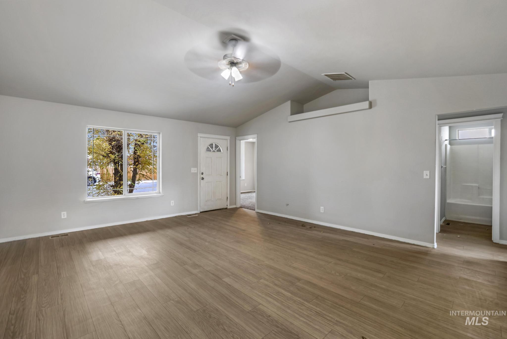Unfurnished living room featuring wood finished floors, vaulted ceiling, and ceiling fan
