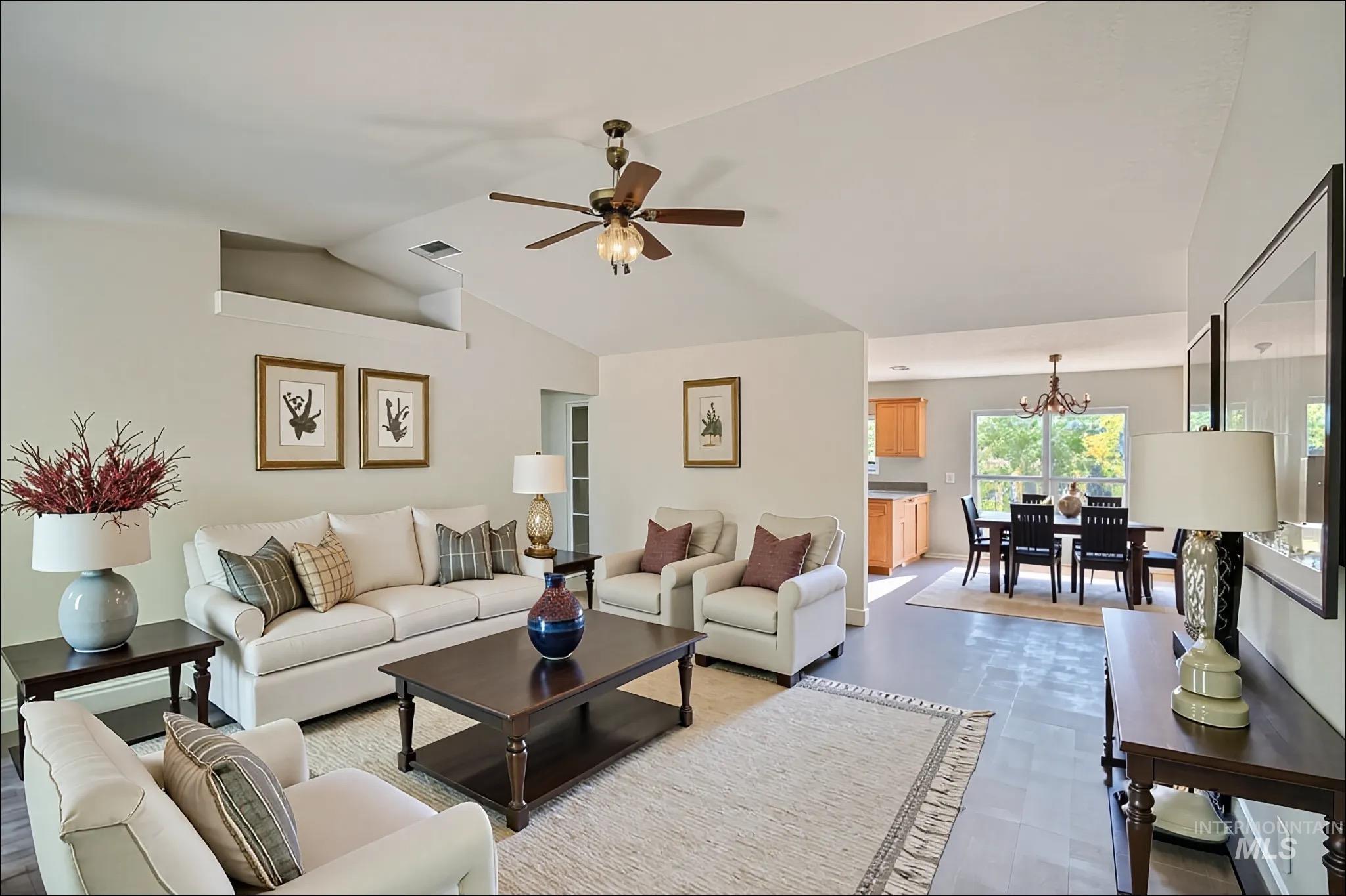 Living area with lofted ceiling, a ceiling fan, and a chandelier