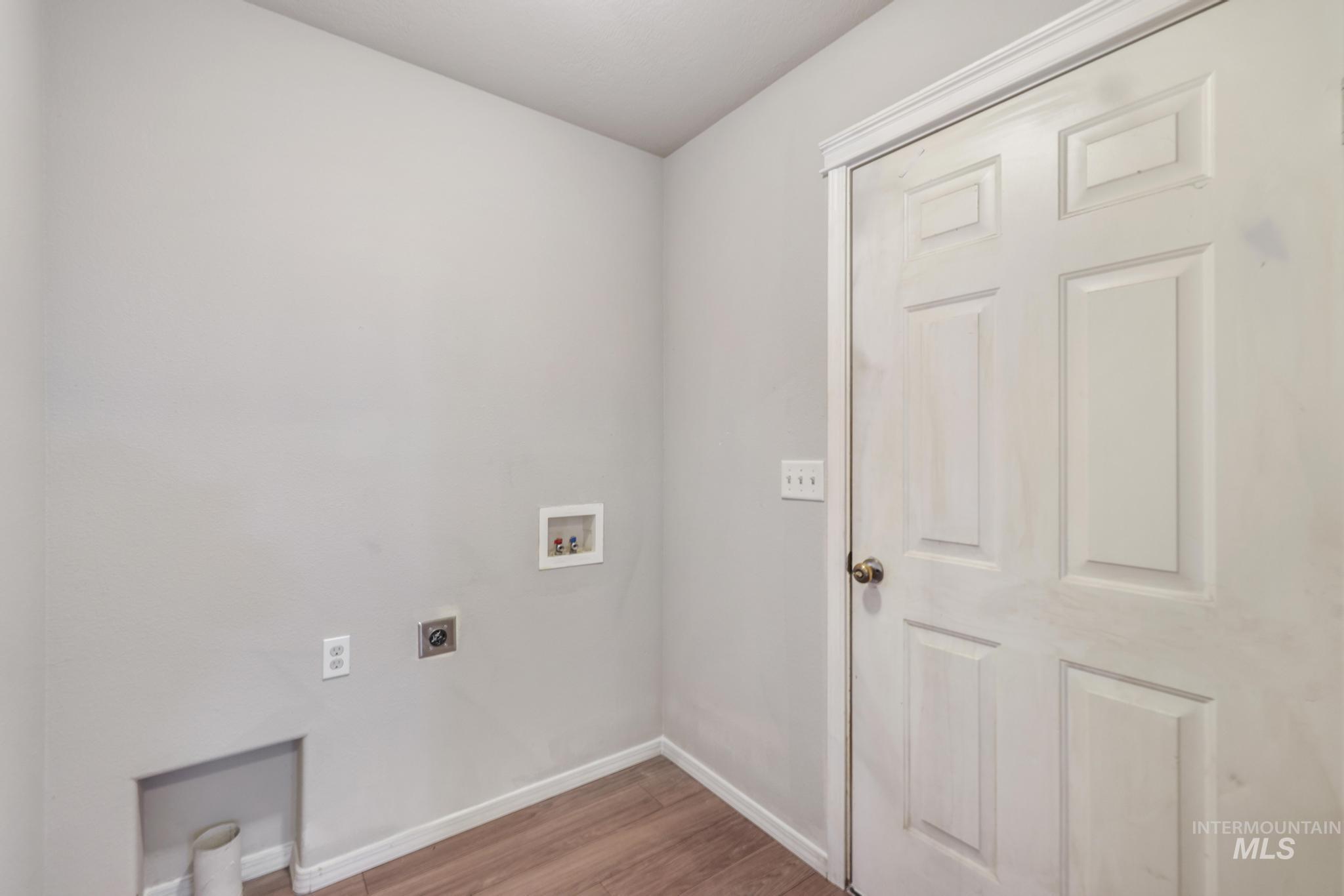 Laundry room with hookup for an electric dryer, hookup for a washing machine, and light wood-type flooring