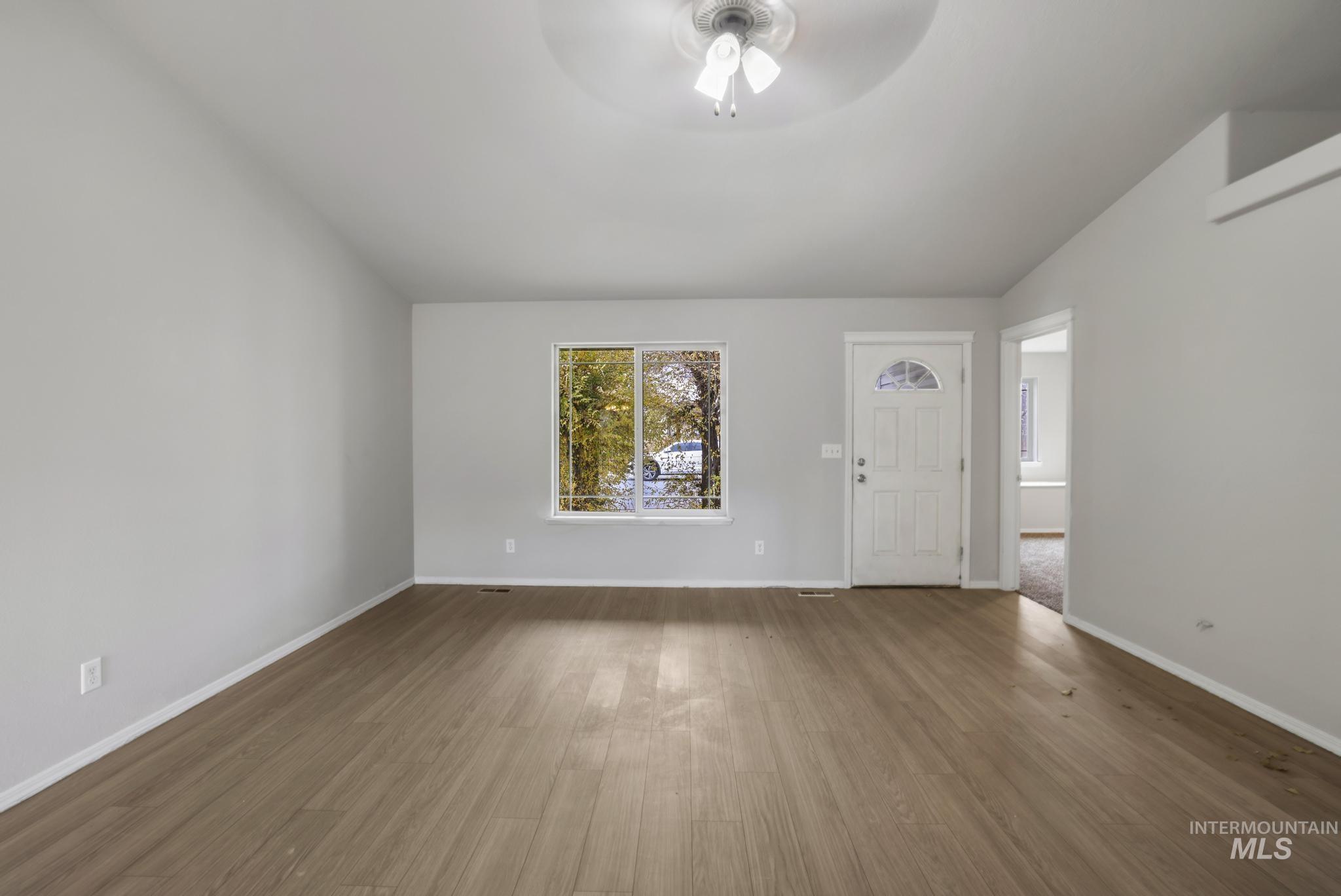 Unfurnished living room with wood finished floors and ceiling fan