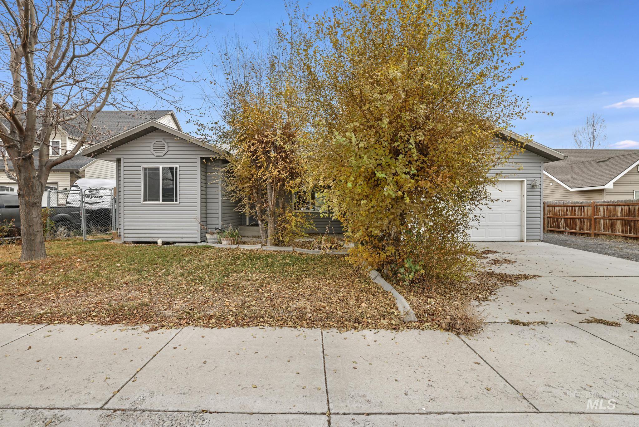 View of property hidden behind natural elements with driveway and a garage