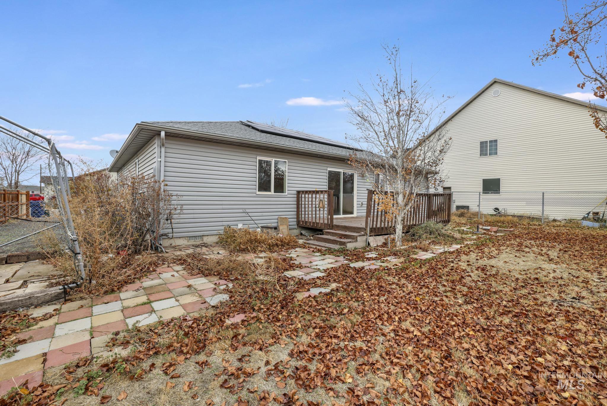 Rear view of house featuring roof mounted solar panels, a deck, and roof with shingles