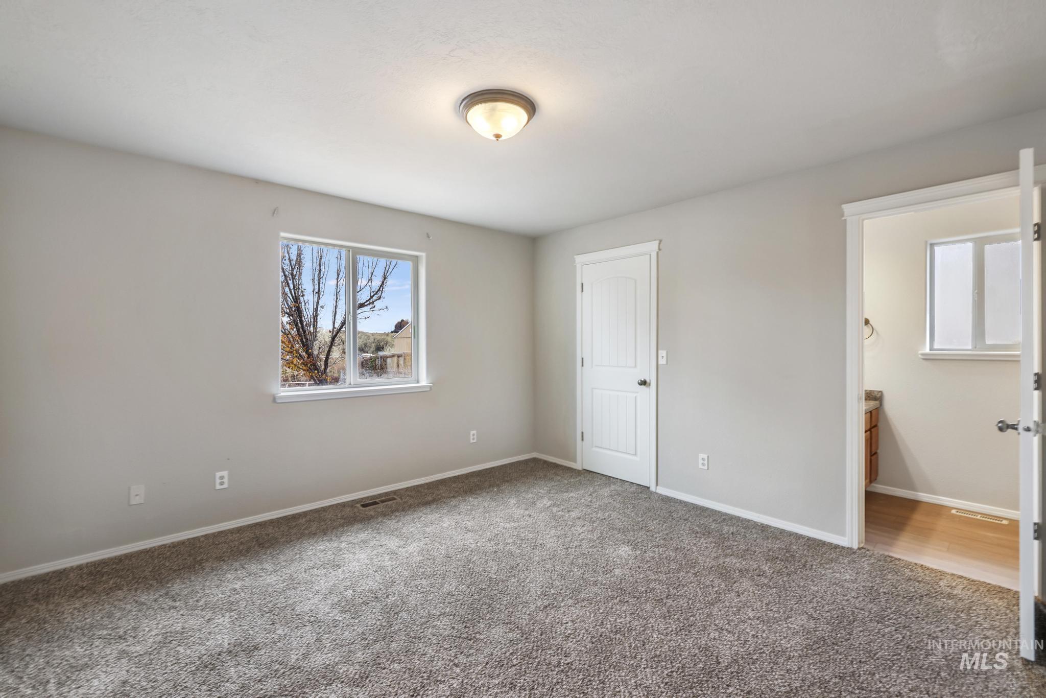 Unfurnished bedroom with carpet floors and ensuite bath