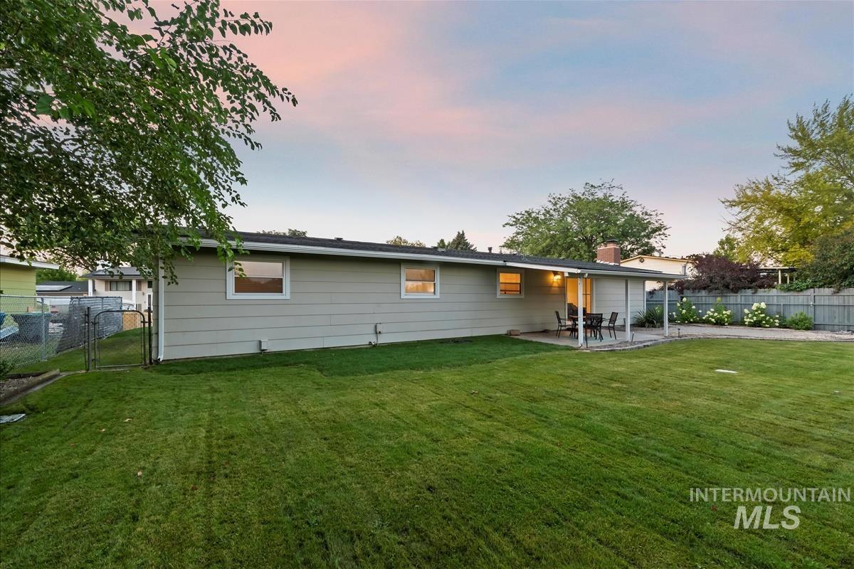 Back of property at dusk with a patio area, a fenced backyard, a gate, and a chimney