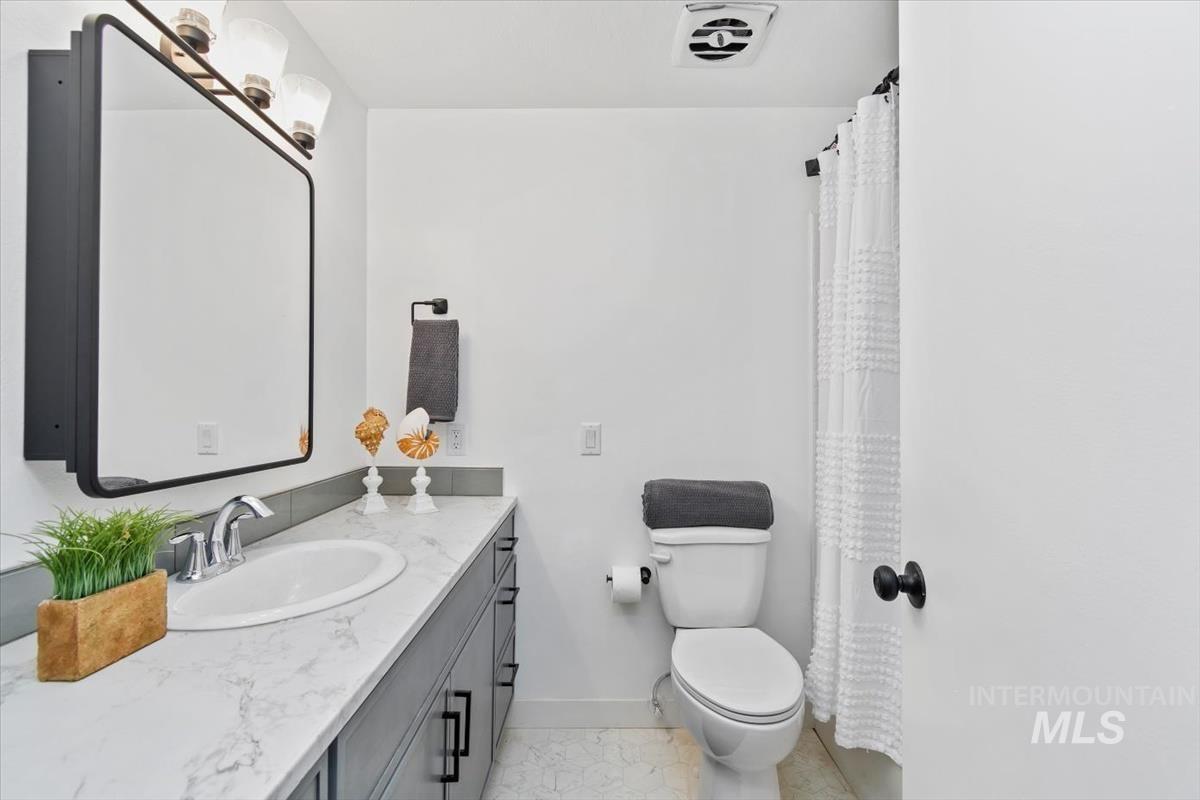 Full bathroom featuring vanity, light tile patterned floors, and a shower with shower curtain