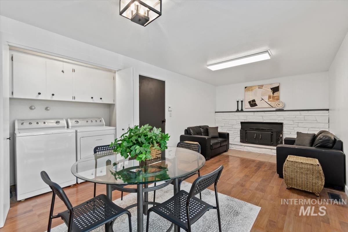 Dining room featuring light wood-style floors, a stone fireplace, and washing machine and dryer