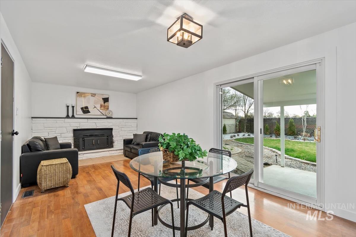 Dining room with a stone fireplace and light wood-style flooring