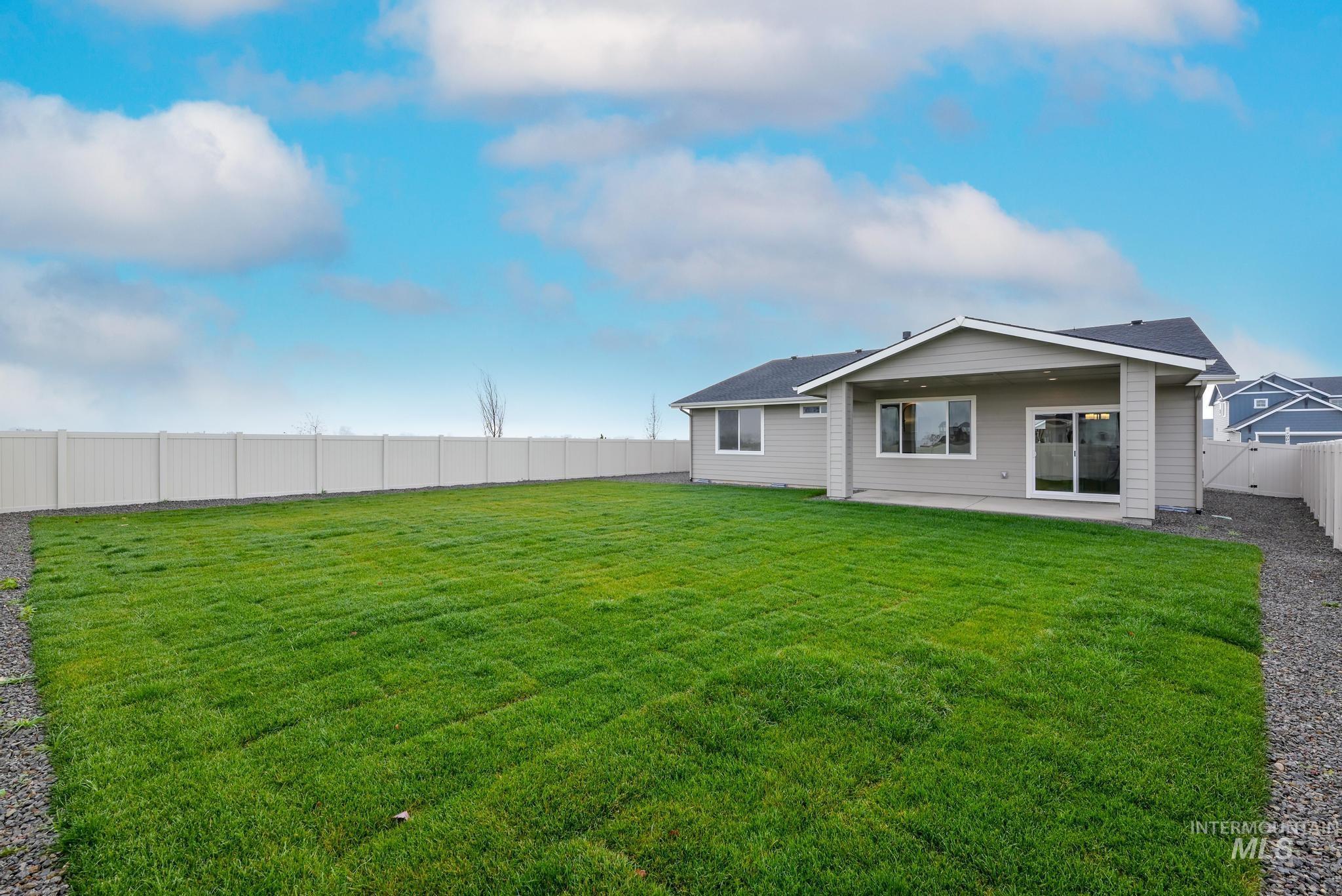 Rear view of house with a fenced backyard and a patio area