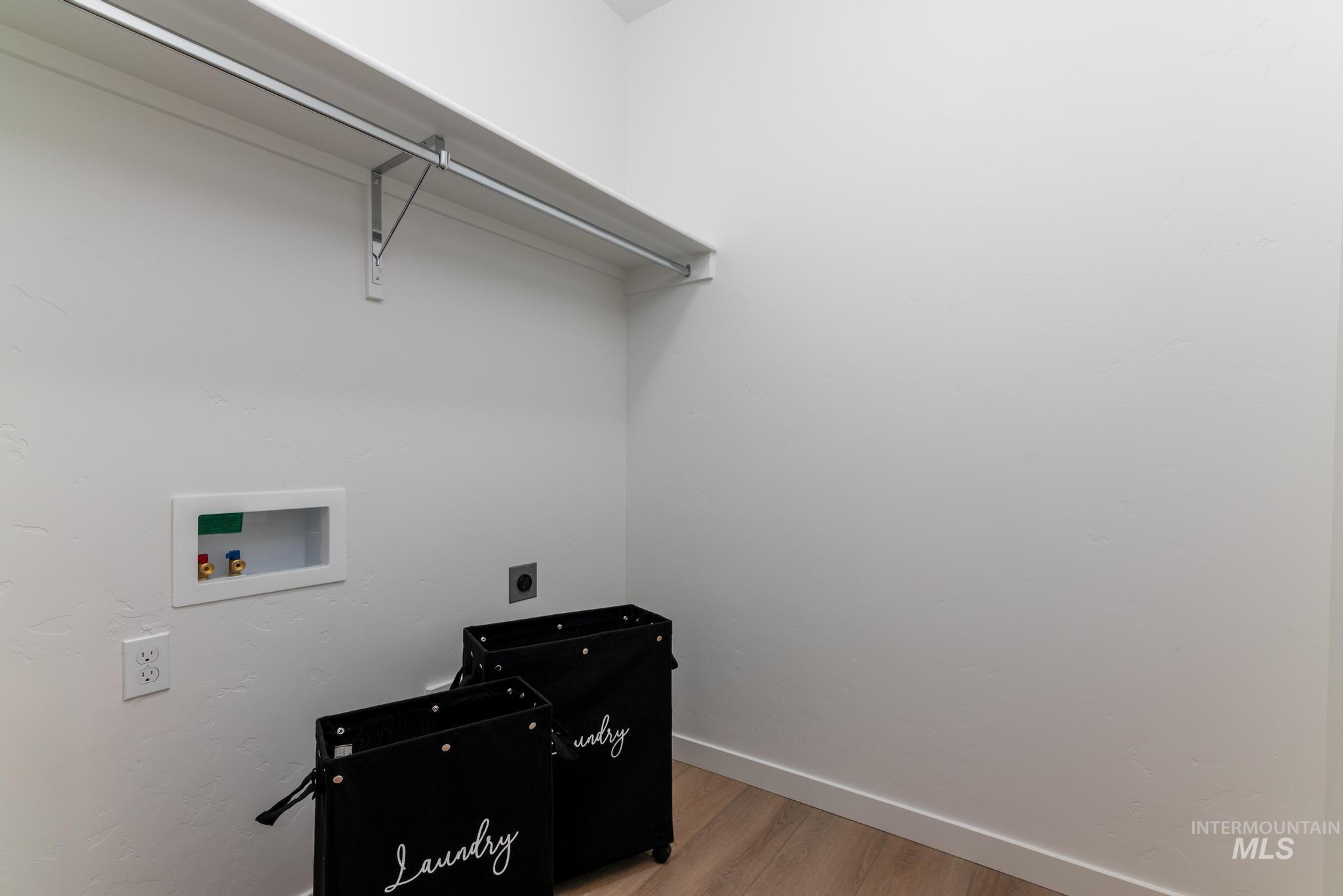 Laundry area with wood finished floors, hookup for a washing machine, and hookup for an electric dryer