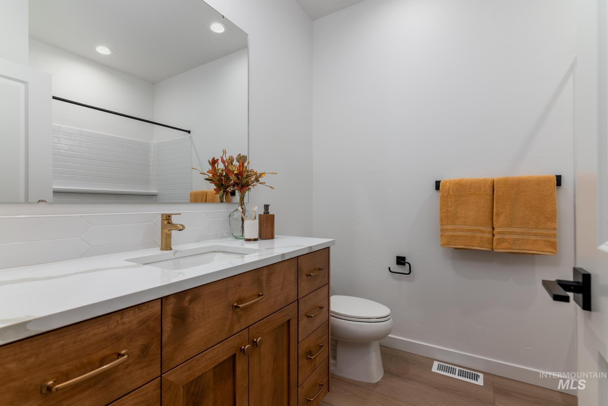 Full bathroom with vanity, backsplash, light wood-style flooring, recessed lighting, and a shower