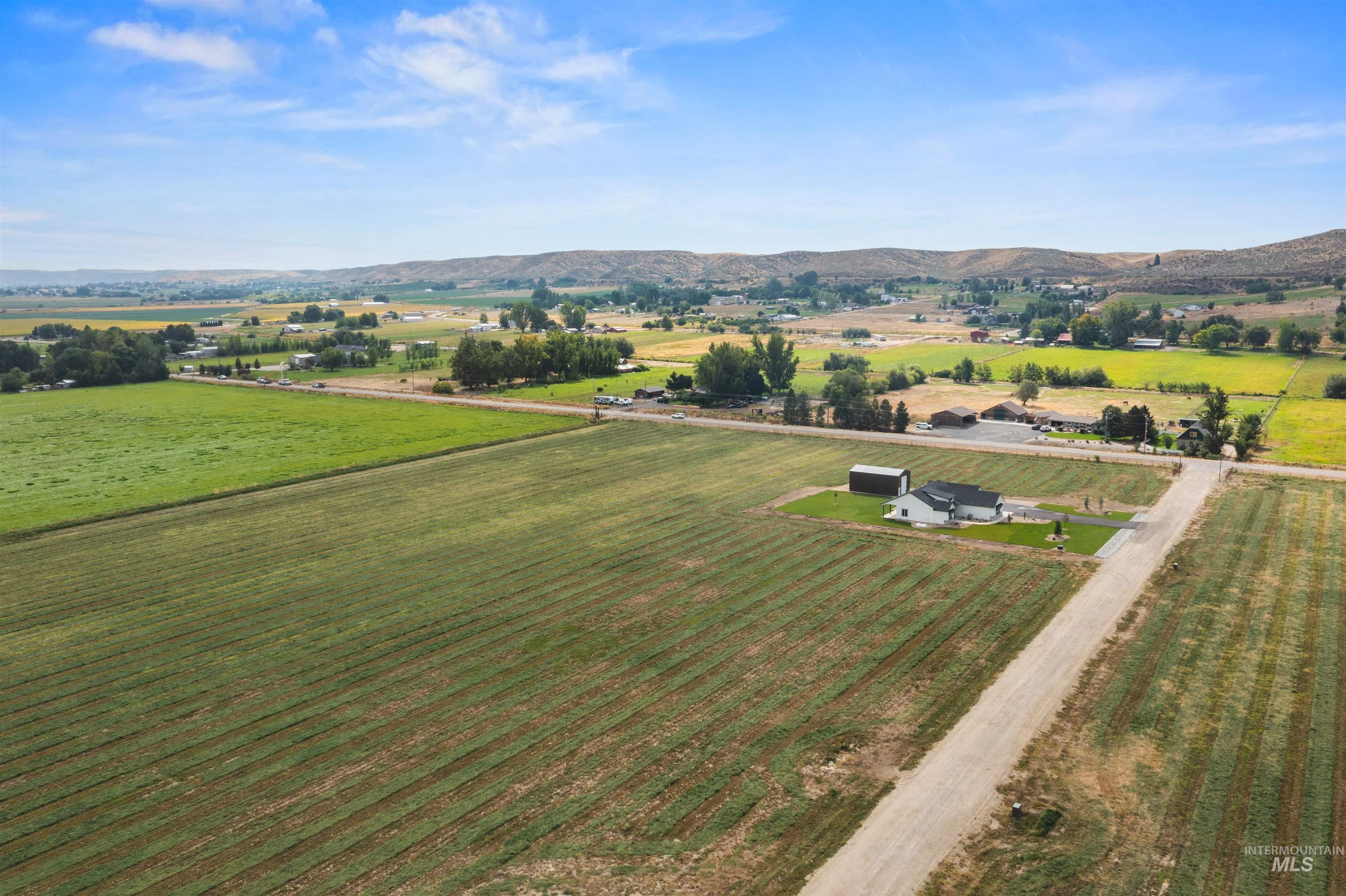 Aerial view of sparsely populated area with a mountainous background and rows of crops