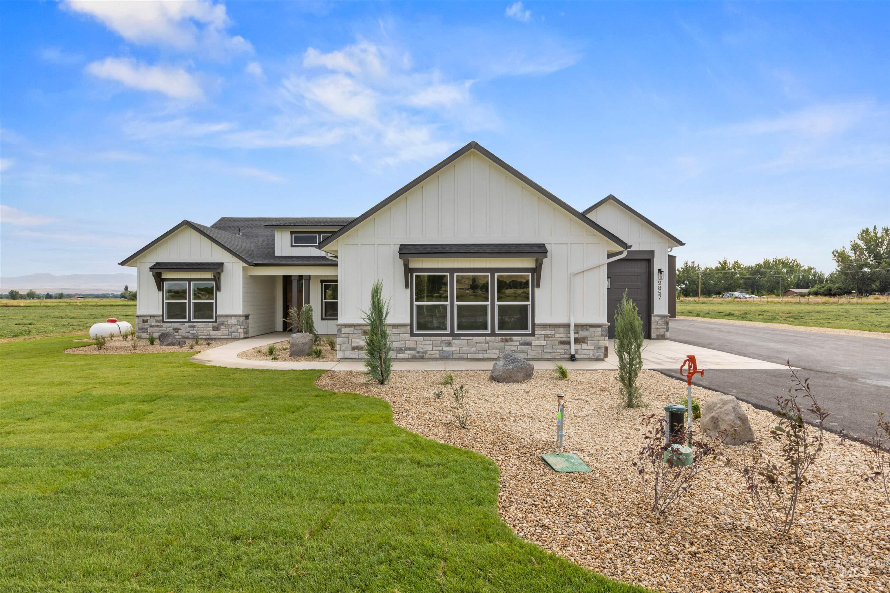 Modern farmhouse style home featuring board and batten siding, stone siding, and asphalt driveway